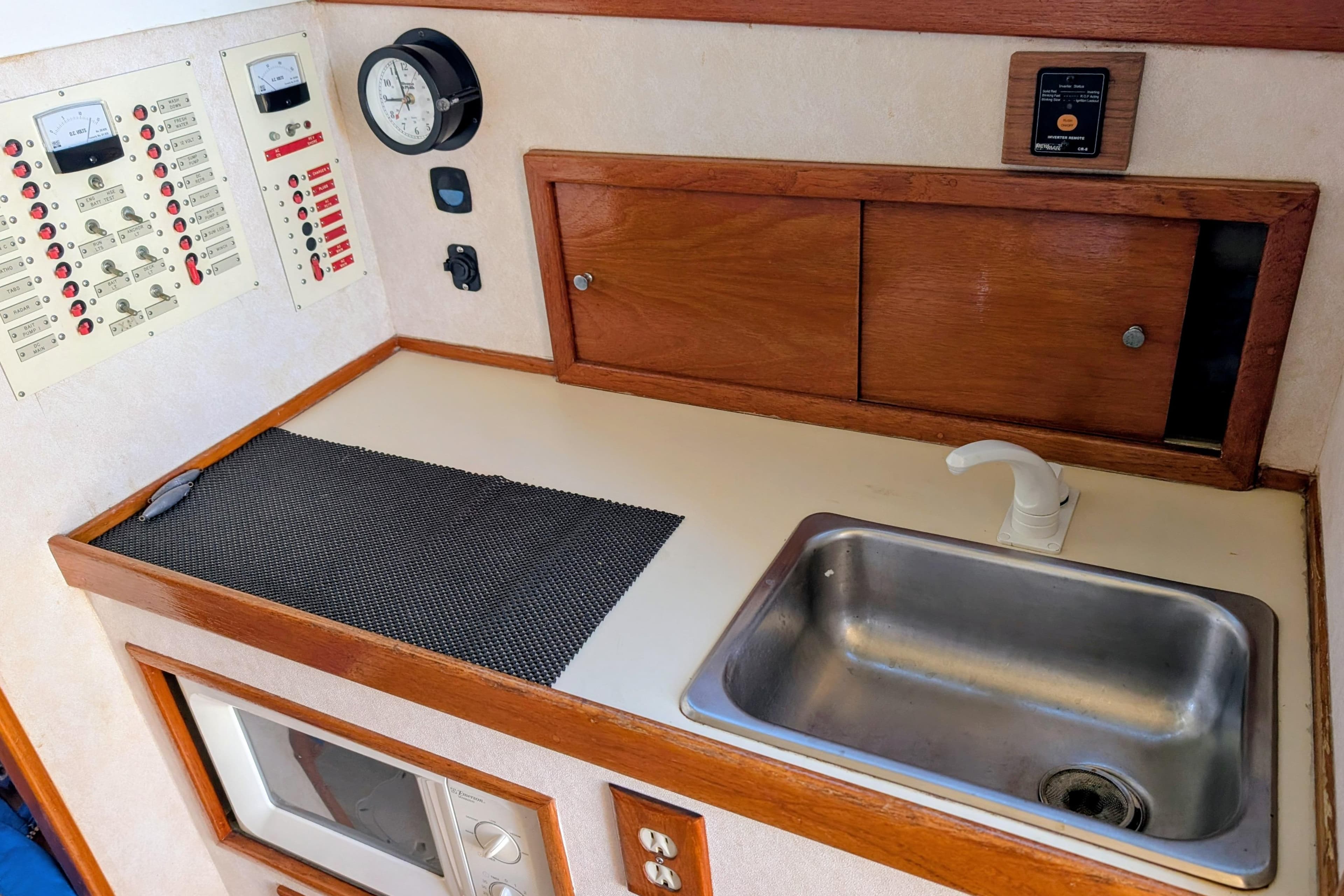1989 Blackman Billfisher 26 boat interior with sink, control panel, and wooden cabinetry.