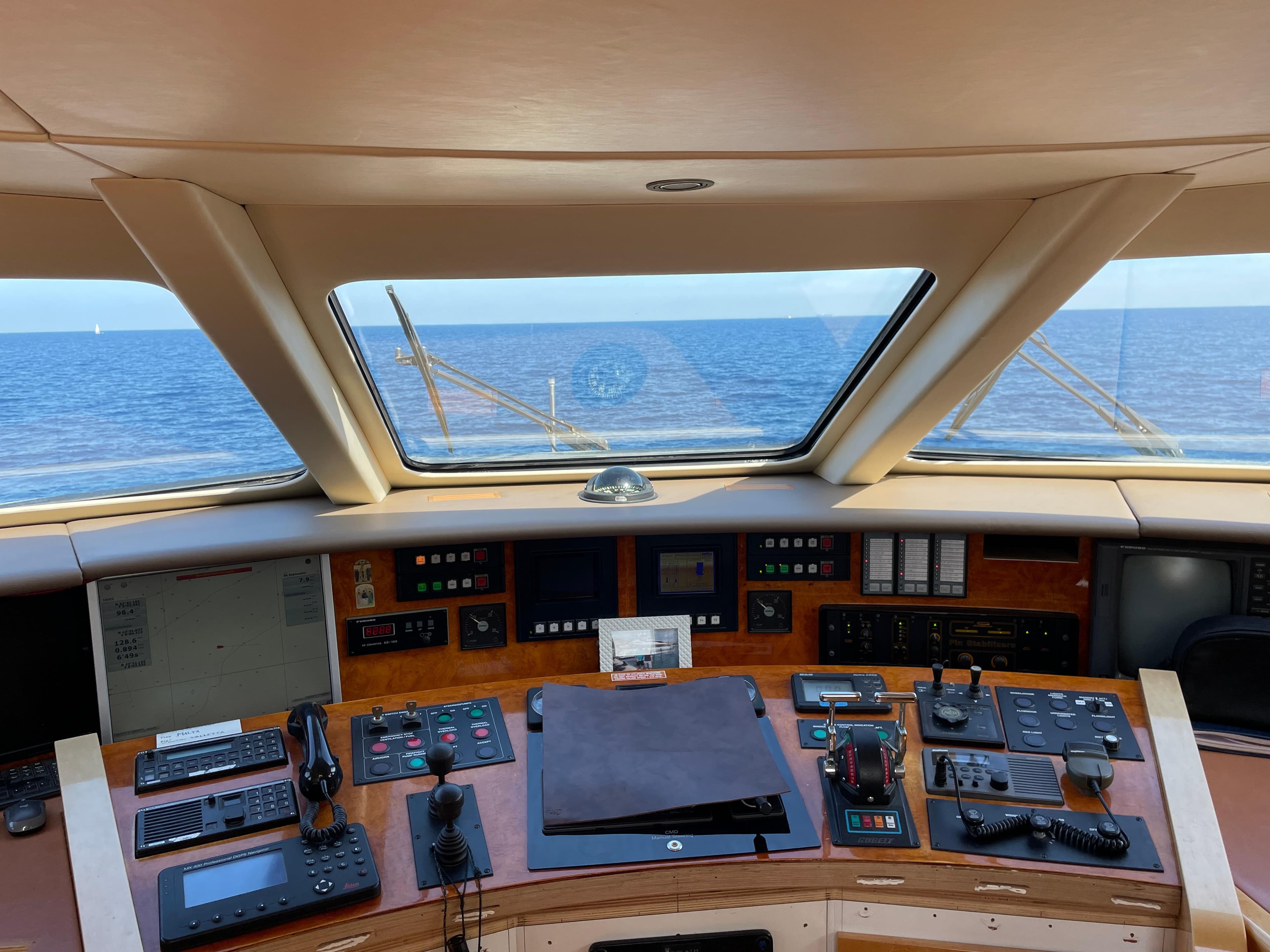 Control panel of 2000 Heesen Versilcraft yacht with ocean view through windows.