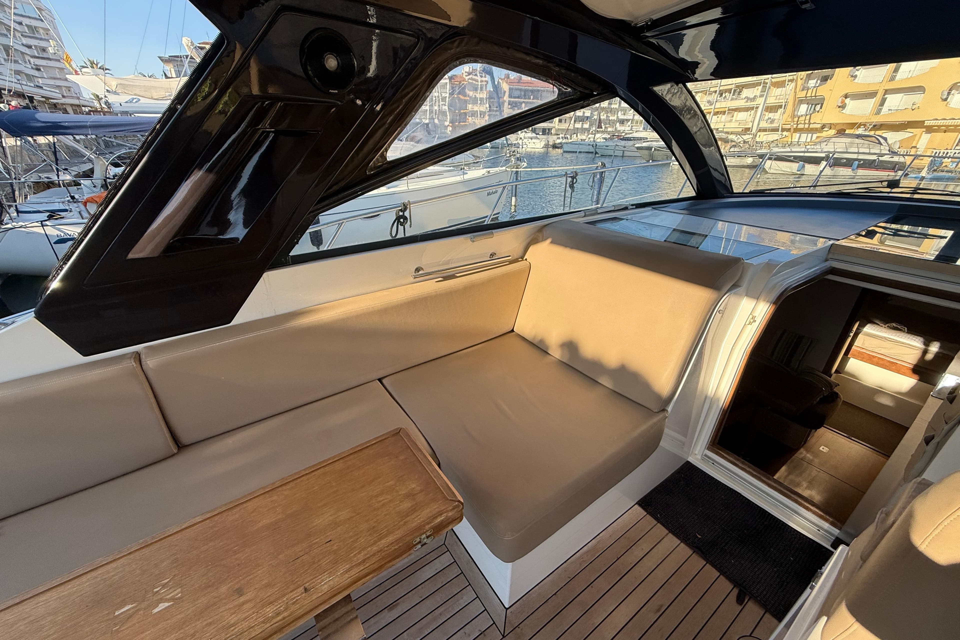 2010 Sealine SC35 yacht interior with beige seating and wooden table in a marina setting.
