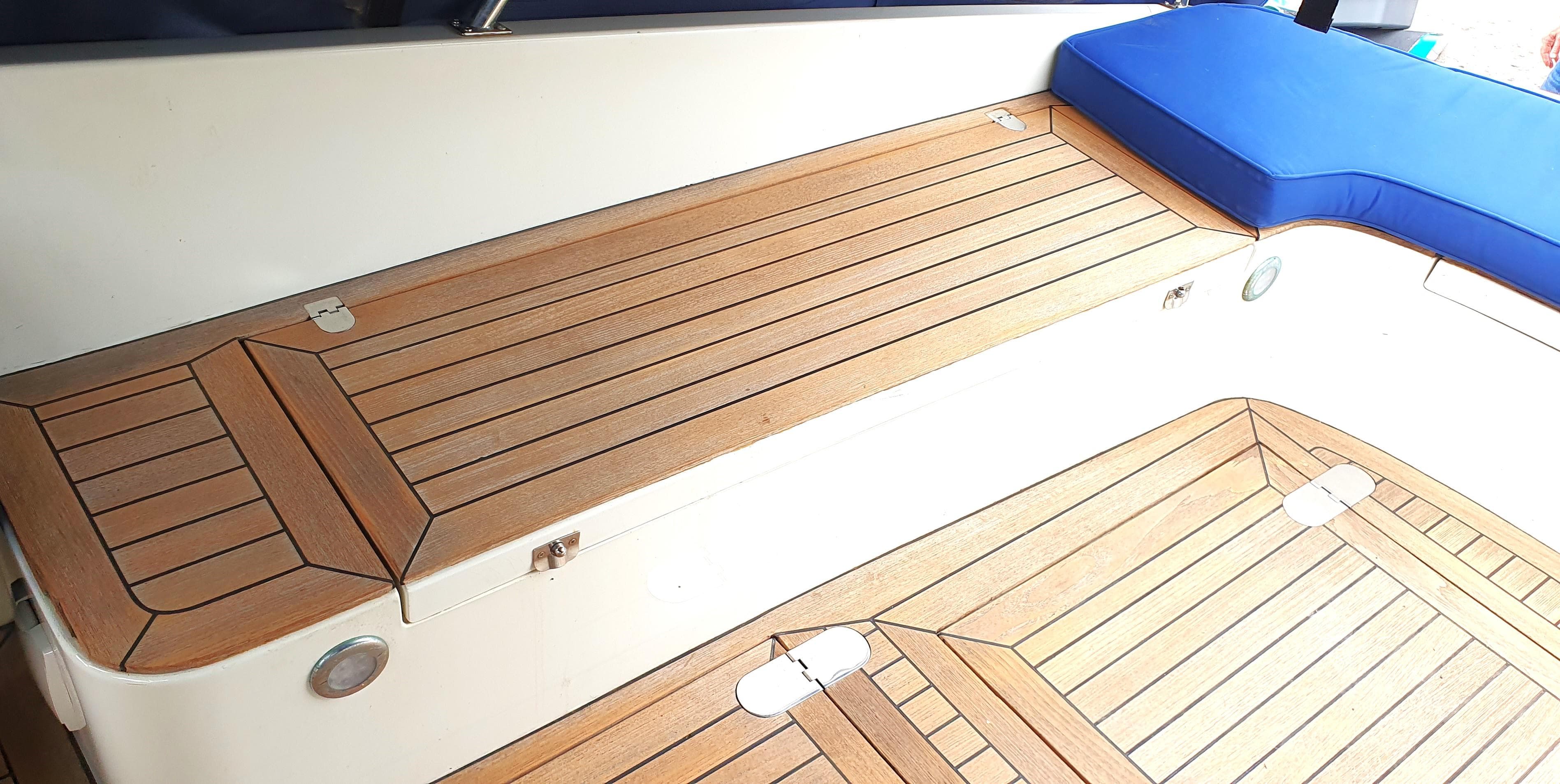 Teak deck of 2006 Swordsman 30 boat with blue cushion.