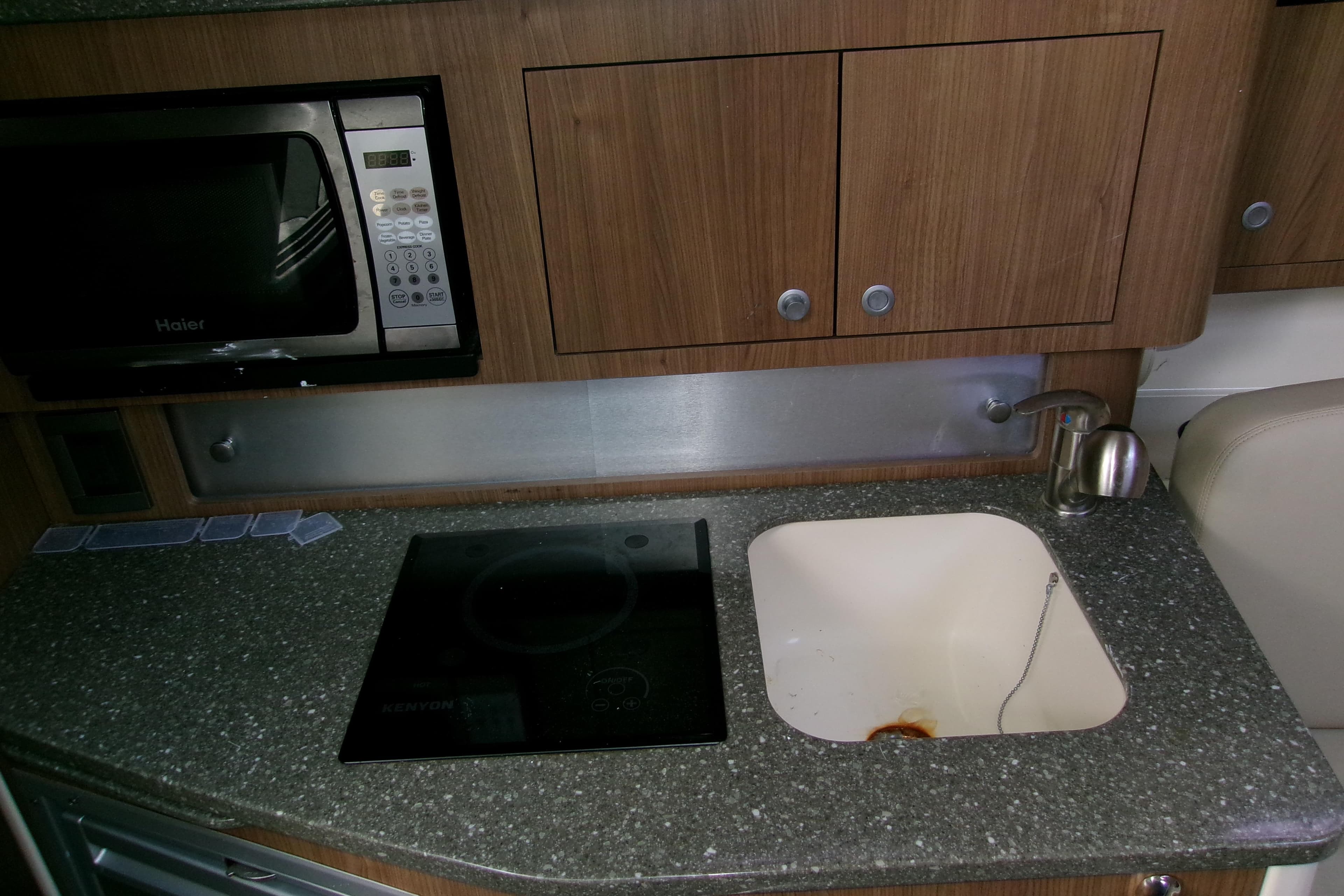 2013 Boston Whaler 315 Conquest kitchen with microwave, sink, and stovetop.