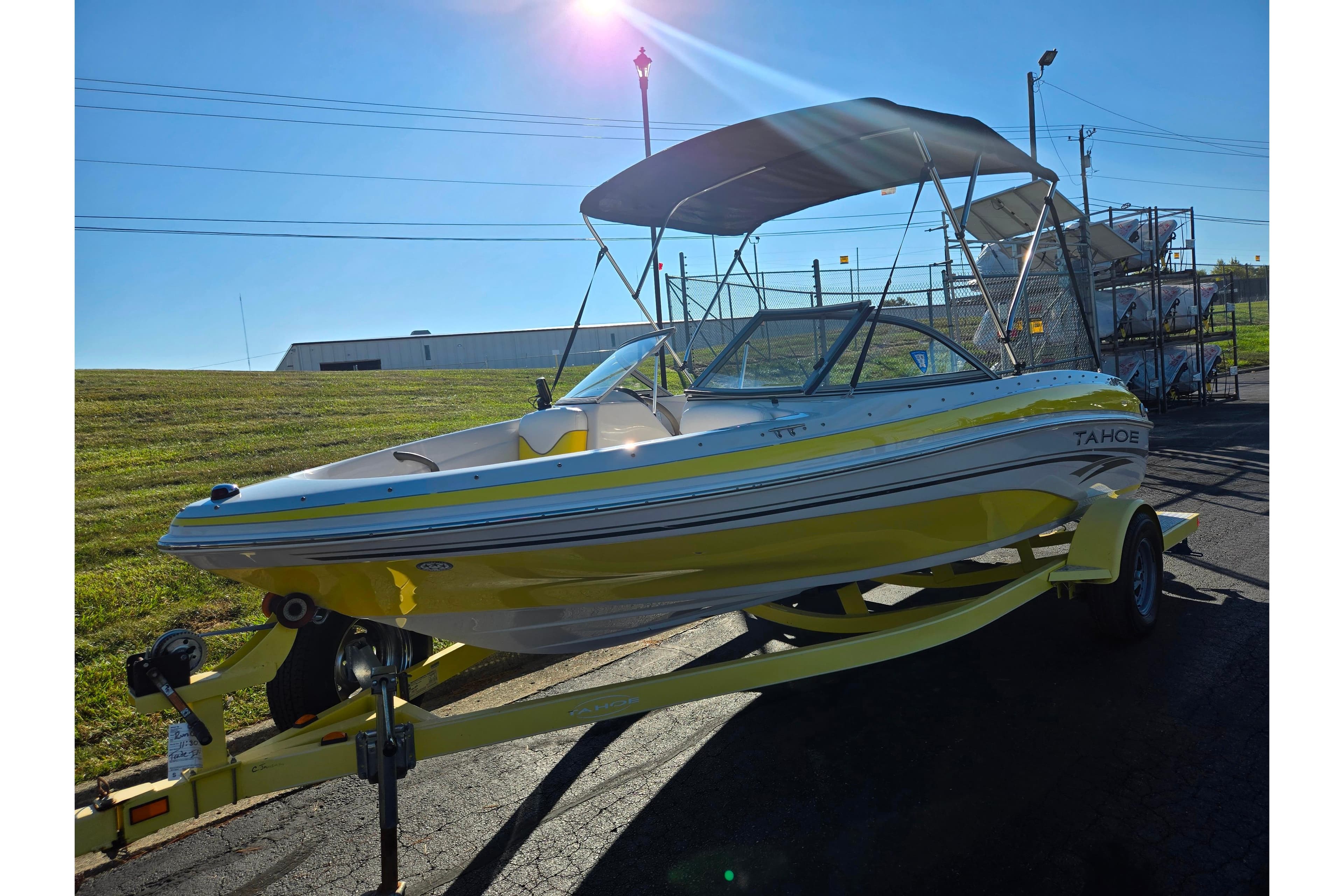 2006 Tahoe Q4 Sport boat on trailer, yellow and white, with canopy, parked outdoors.