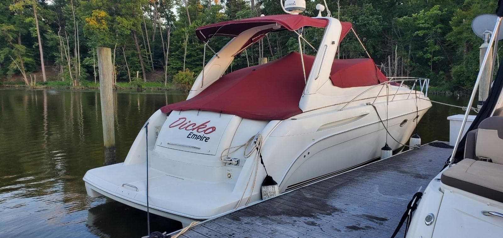 2002 Formula 37 PC boat docked with red cover, surrounded by trees.