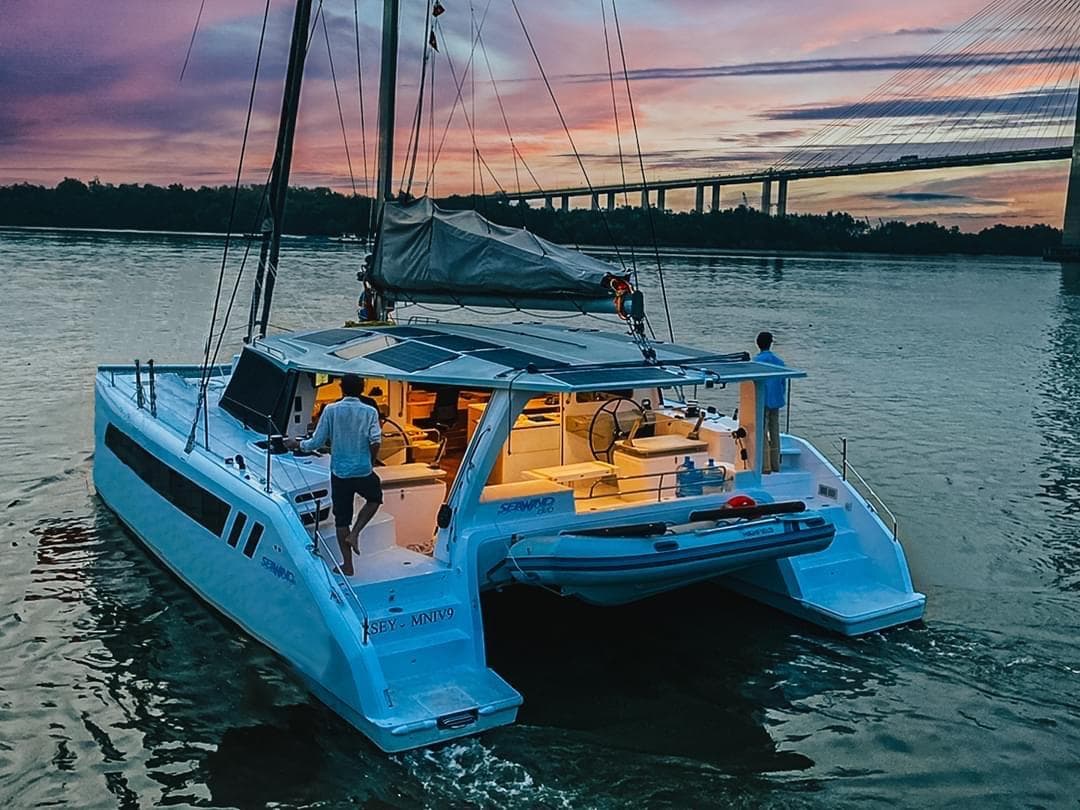 Seawind 1370 catamaran sailing at sunset near a bridge, 2025 model.