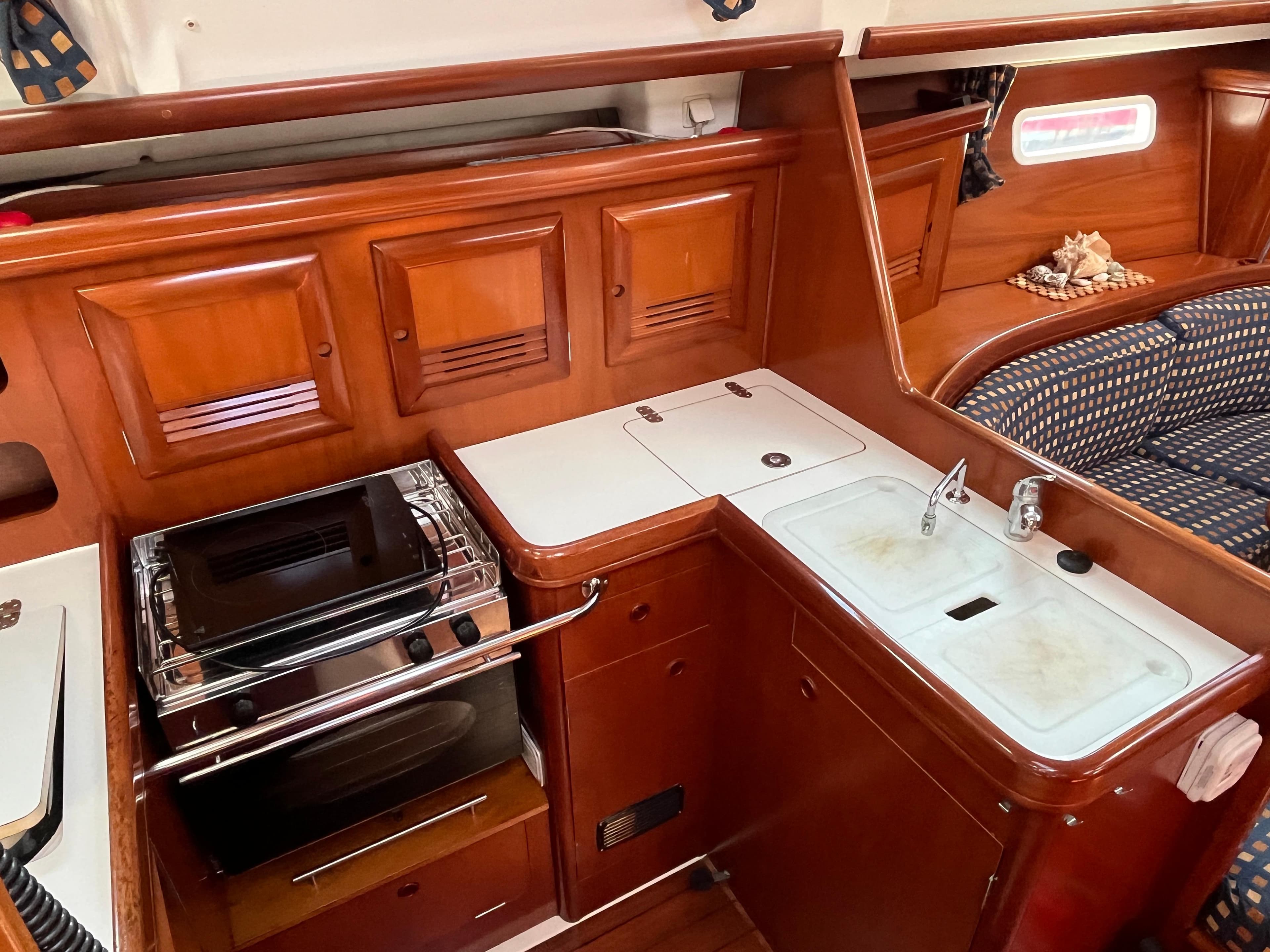 Interior of 2001 Beneteau Oceanis 393 yacht with wooden cabinetry and compact kitchen area.