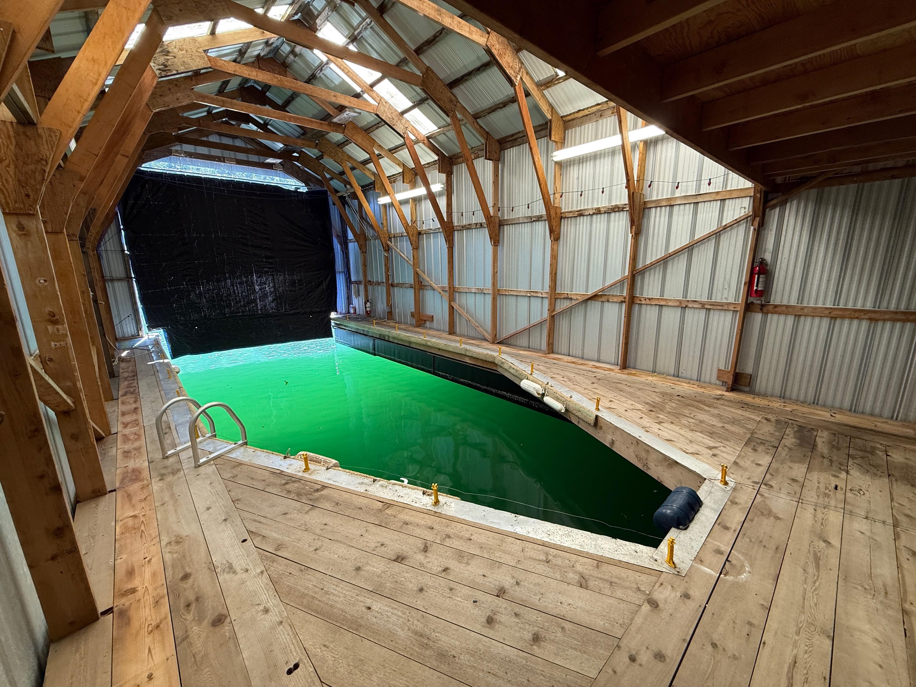 Indoor boathouse with green water, wooden beams, and metal walls, Custom model, 1997.