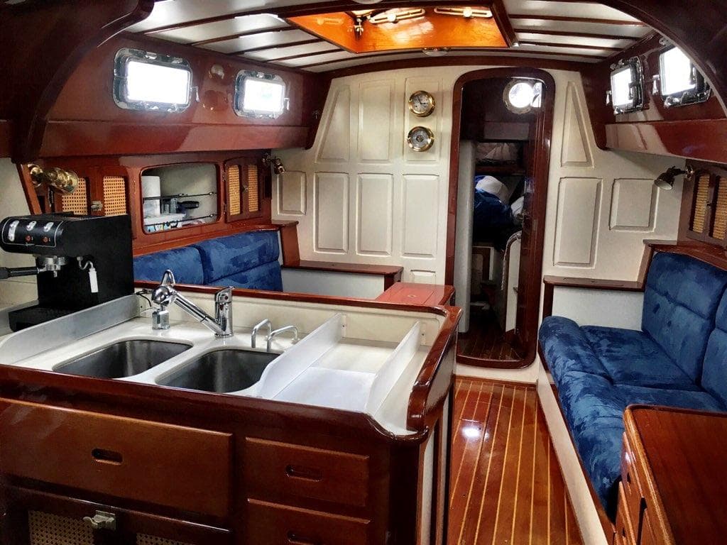 Interior of 2000 Cherubini Schooner with wood finish, blue seating, and kitchen area.