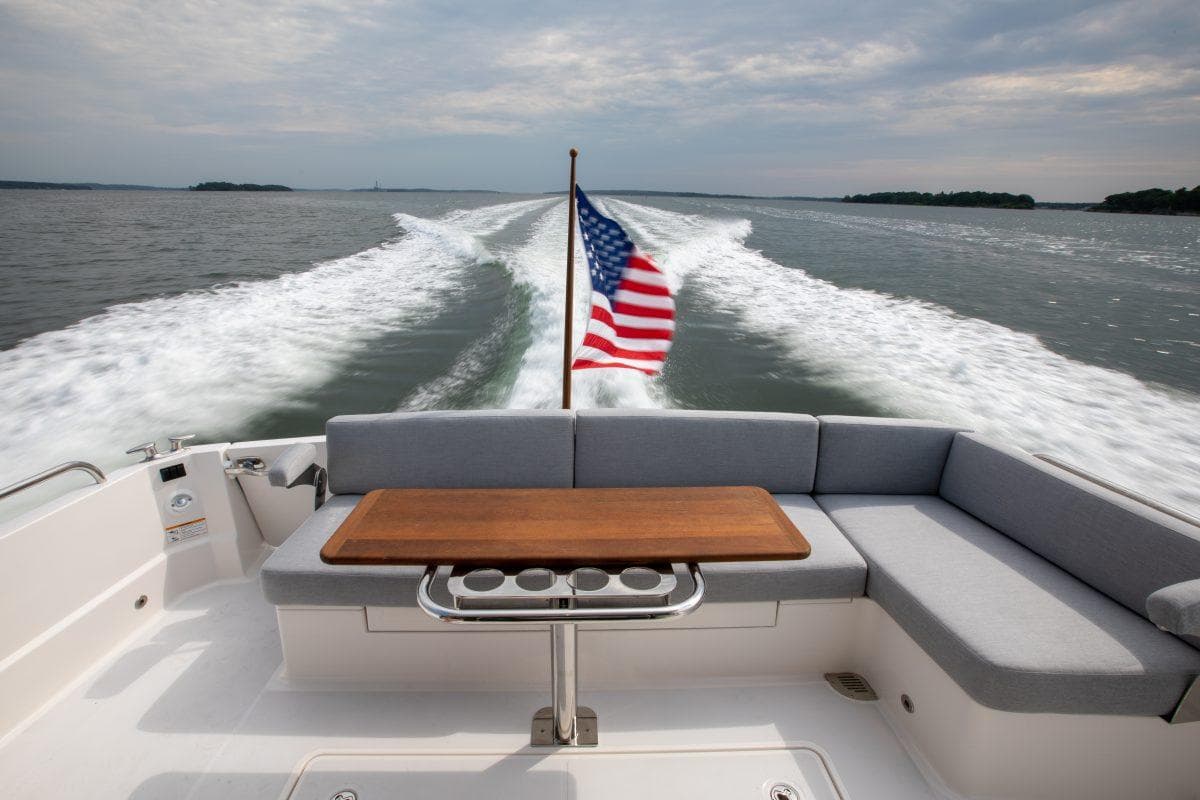 2026 Sabre 43 Salon Express cruising with American flag, spacious seating, and scenic water view.