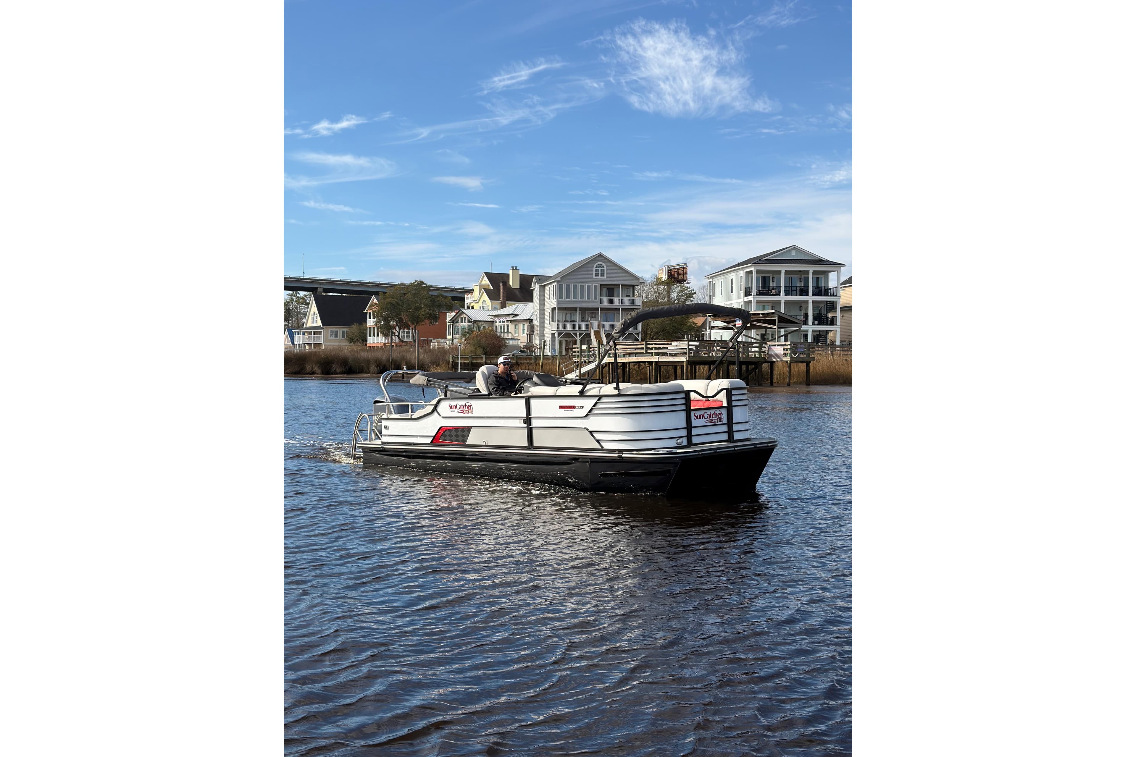 2025 SunCatcher ELITE SERIES 324 SS pontoon boat cruising on a scenic waterway.