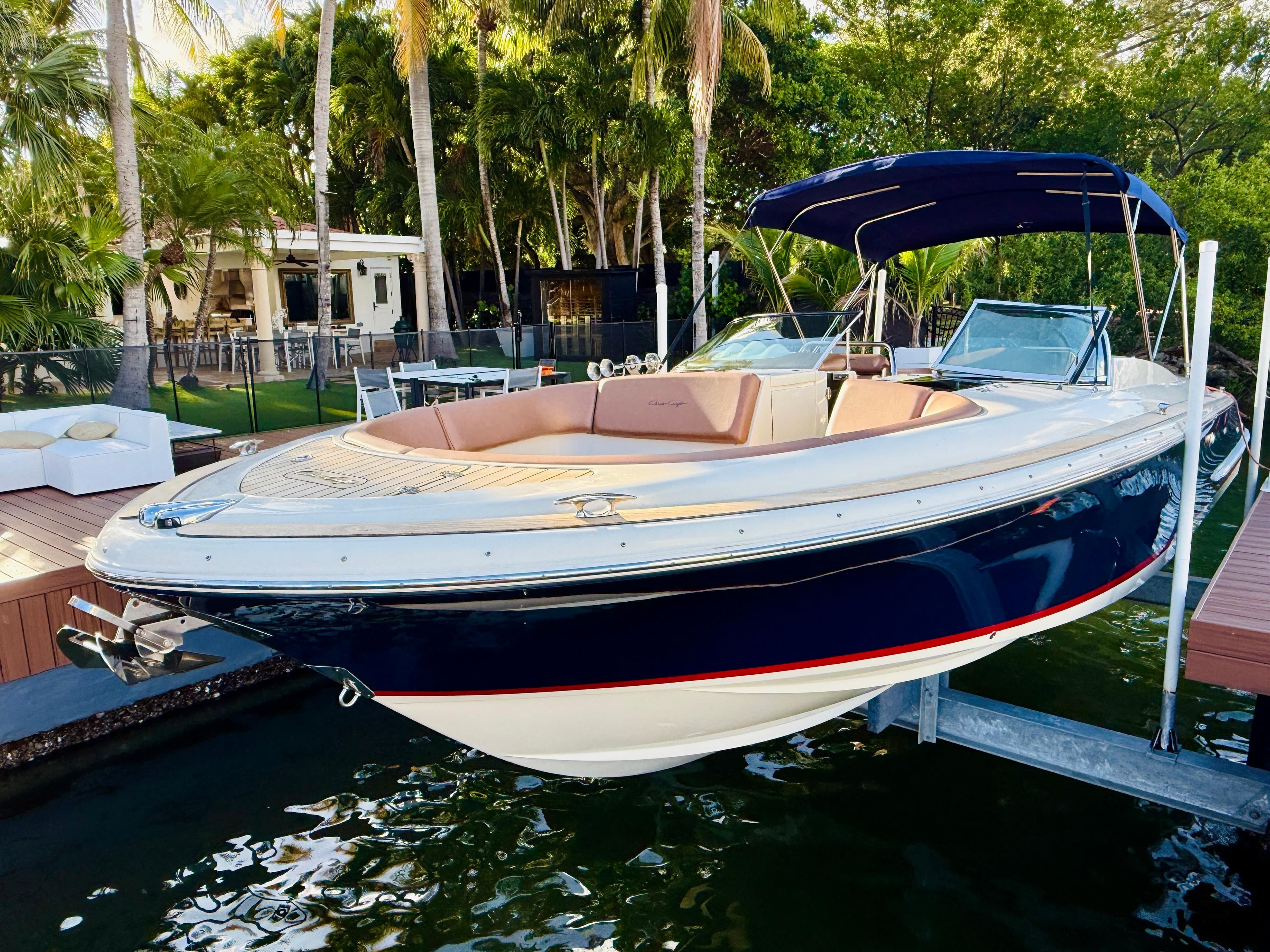 2015 Chris-Craft Launch 32 boat docked near a tropical setting with lush greenery.