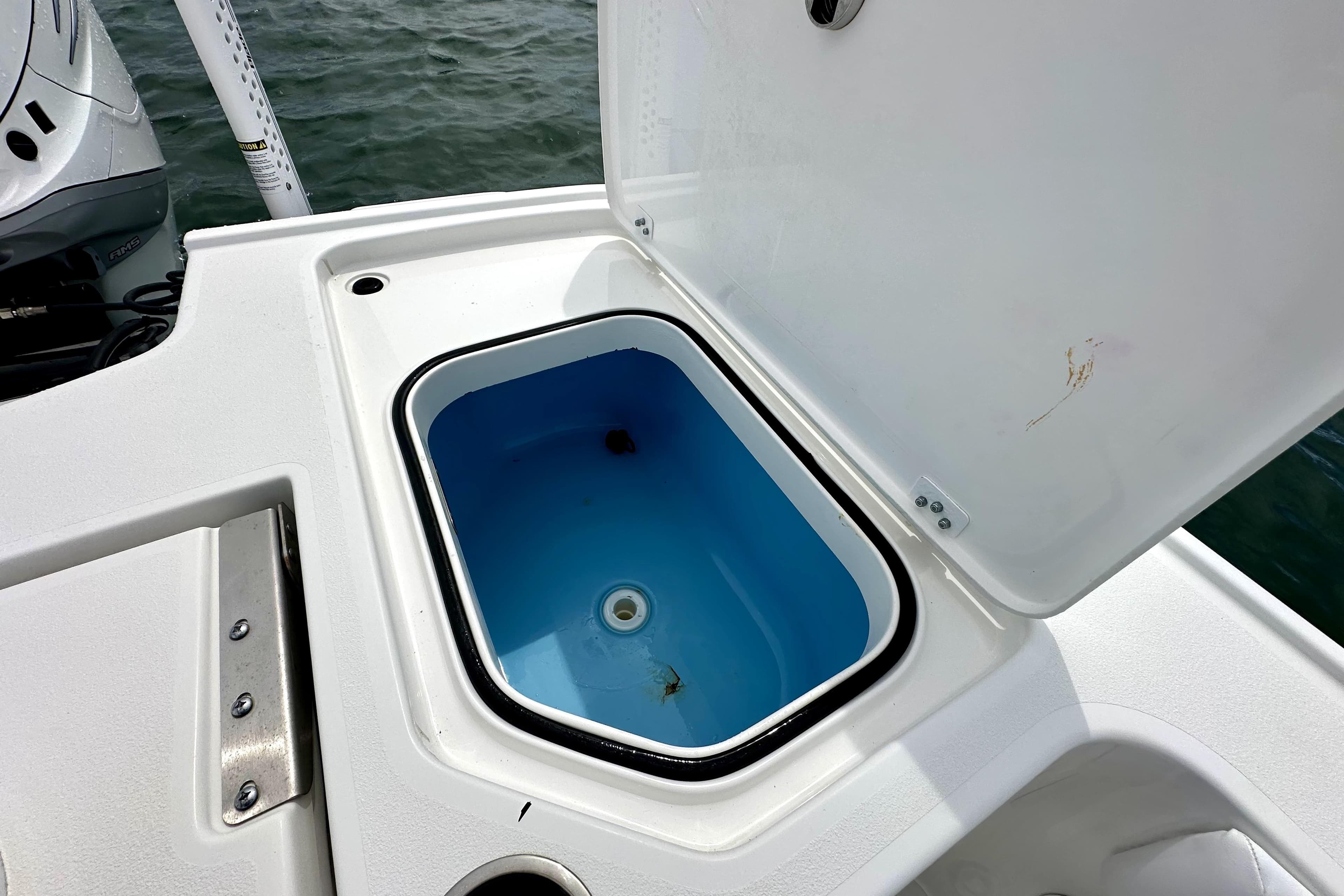 Open storage compartment on 2020 Caymas 26 HB boat, near water.