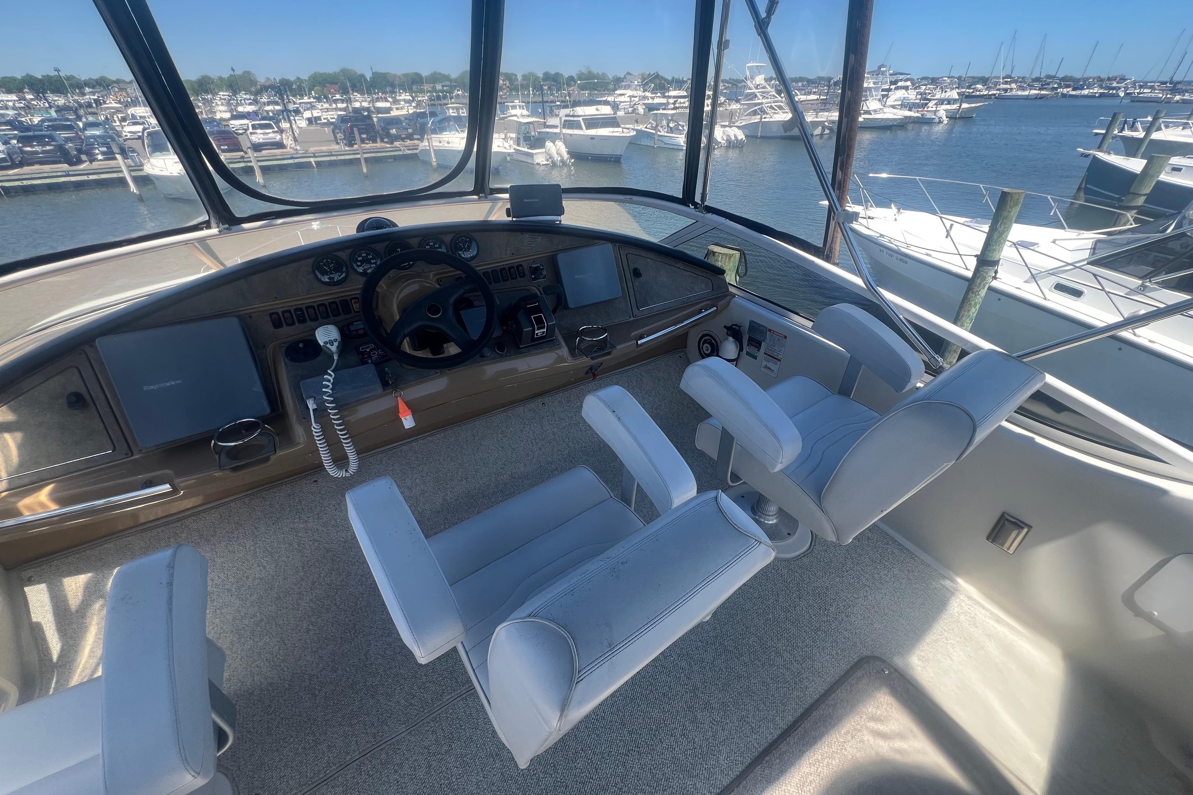 2004 Carver 360 Sport Sedan helm with marina view, featuring dual captain chairs and navigation controls.
