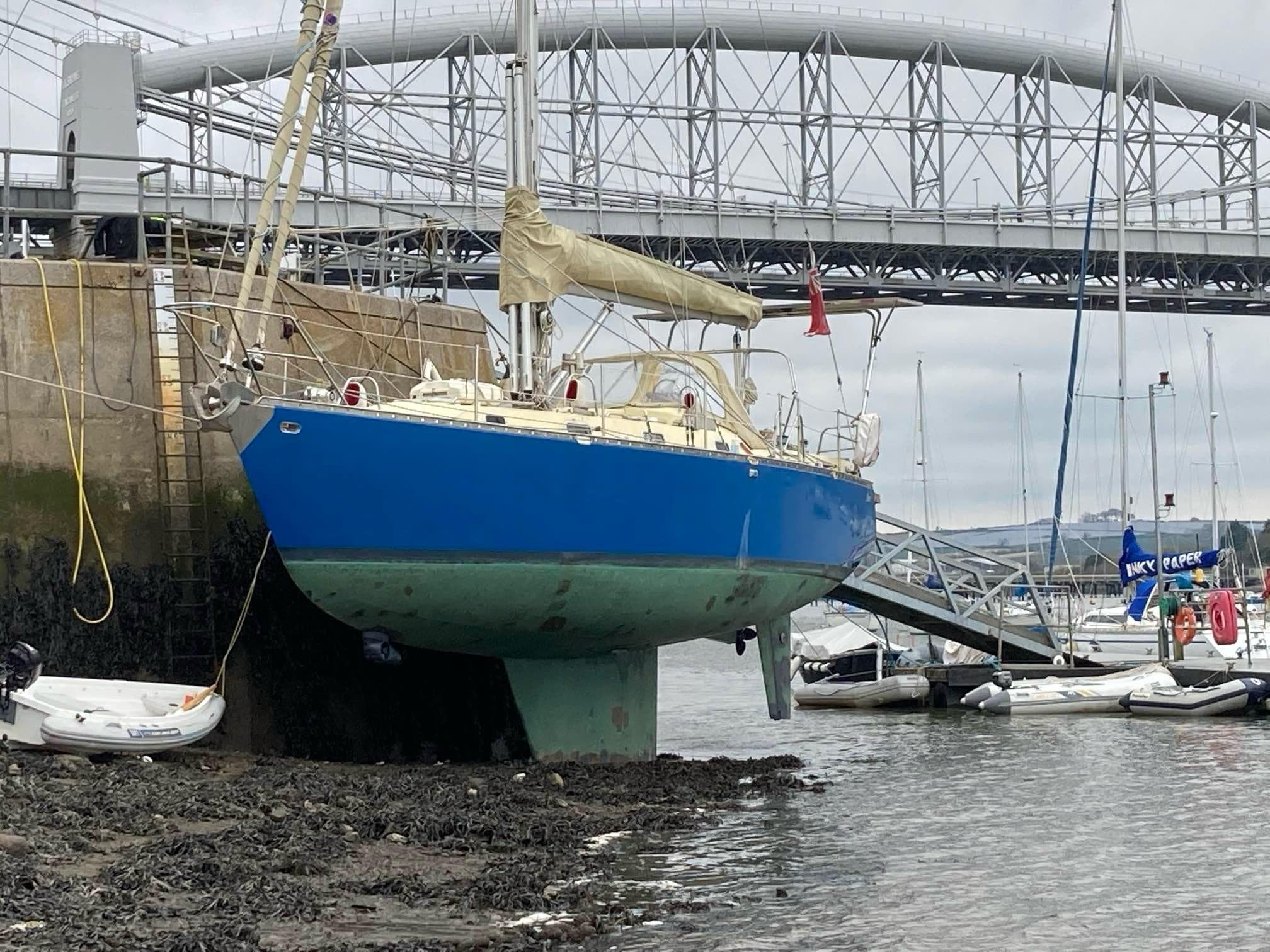 Blue Bruce Roberts Spray A370 sailboat docked near a bridge, 2014 model.