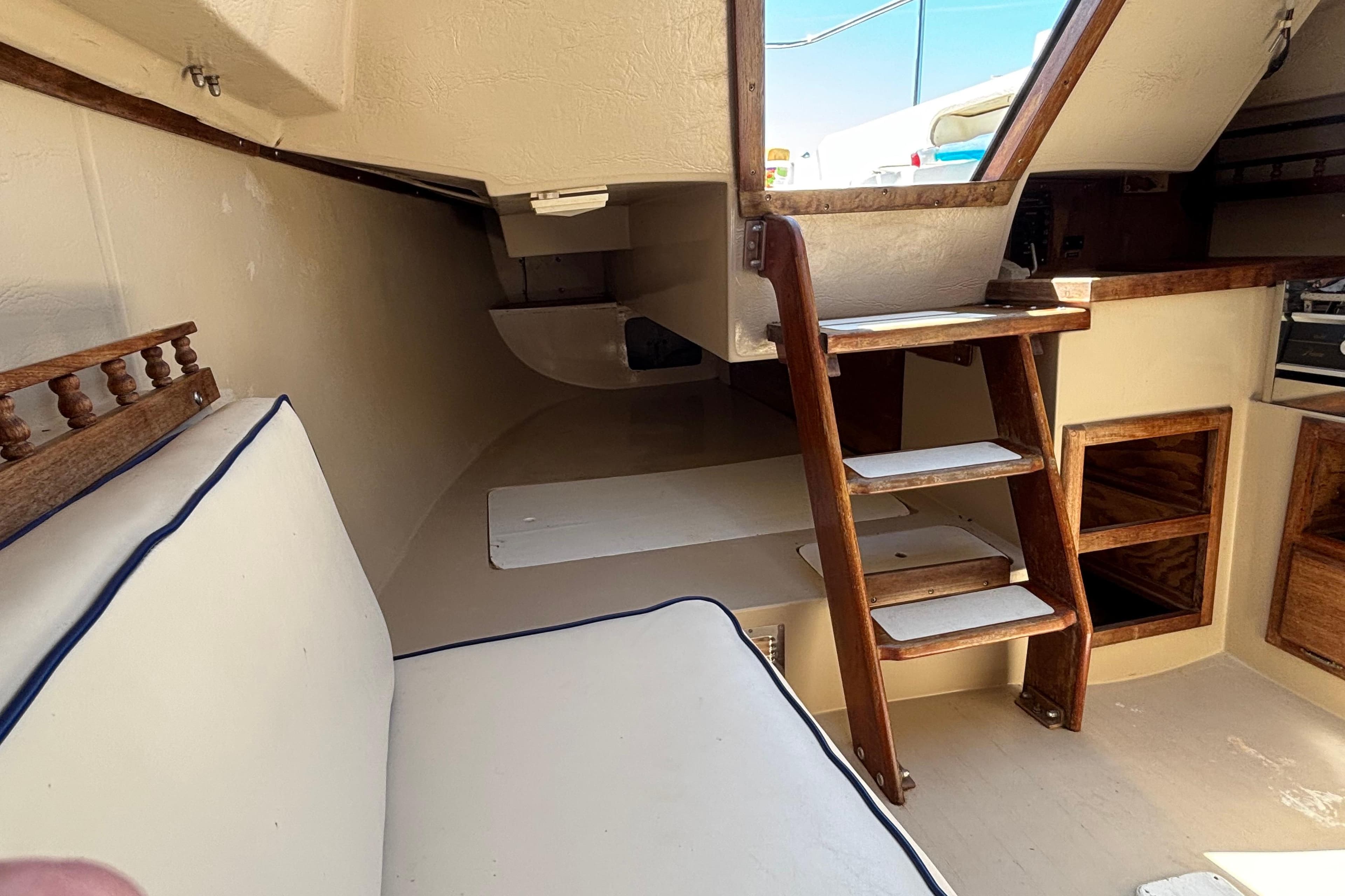 Interior of a 1983 Catalina 25 sailboat with wooden steps and cushioned seating.