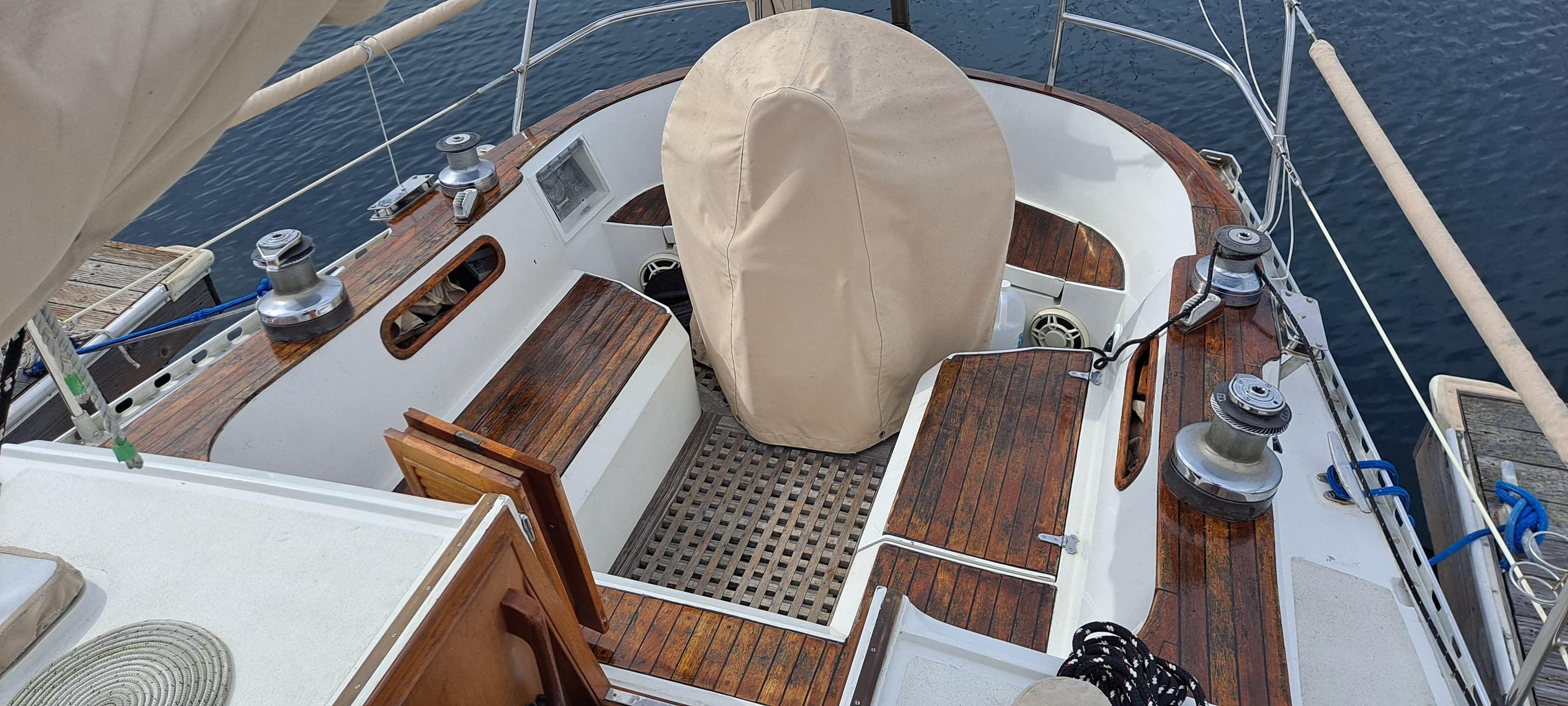 1985 Cheoy Lee Pedrick 38w sailboat cockpit with wooden accents and covered steering wheel.