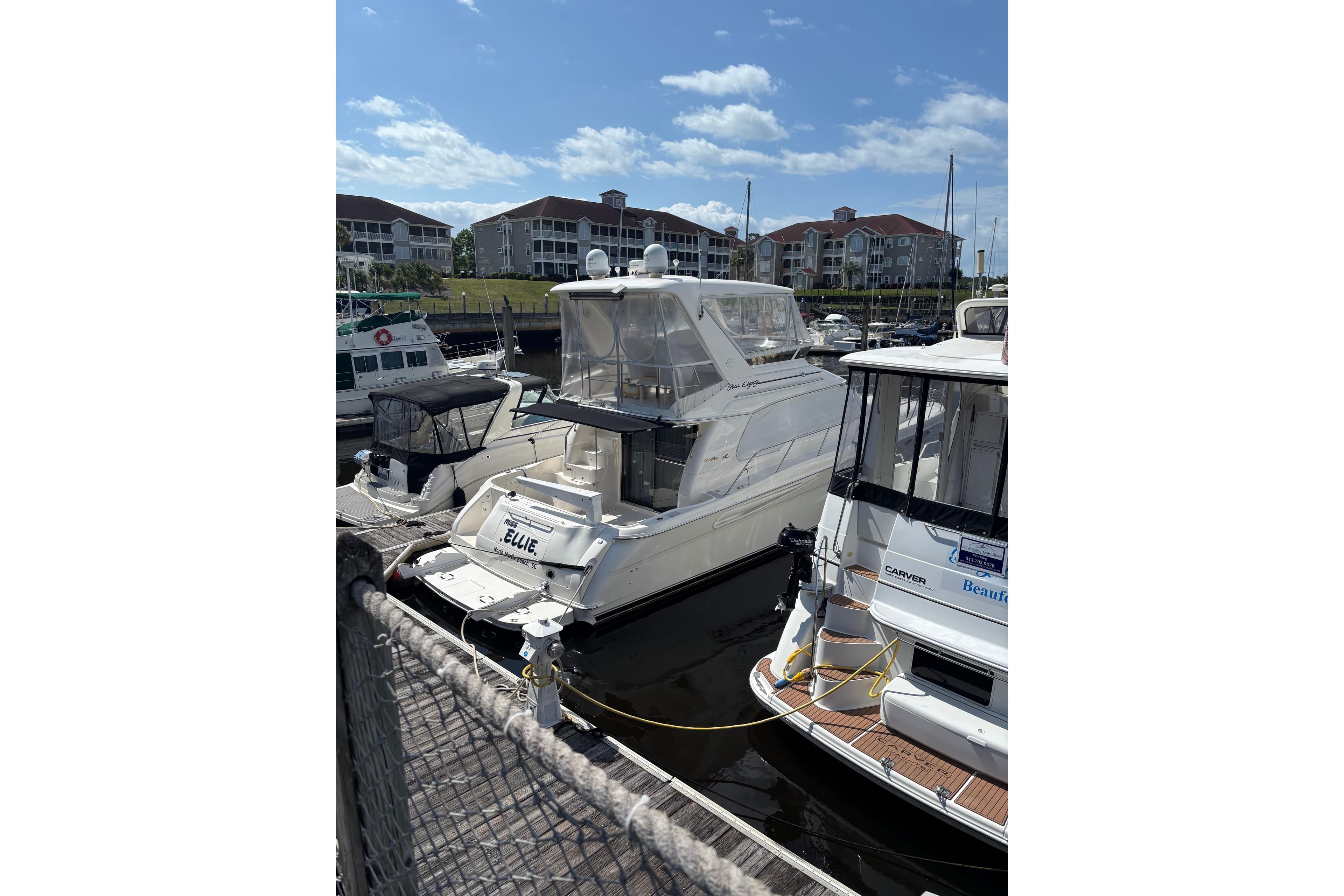 1999 Sea Ray 480 Sedan Bridge yacht docked at marina under blue sky.