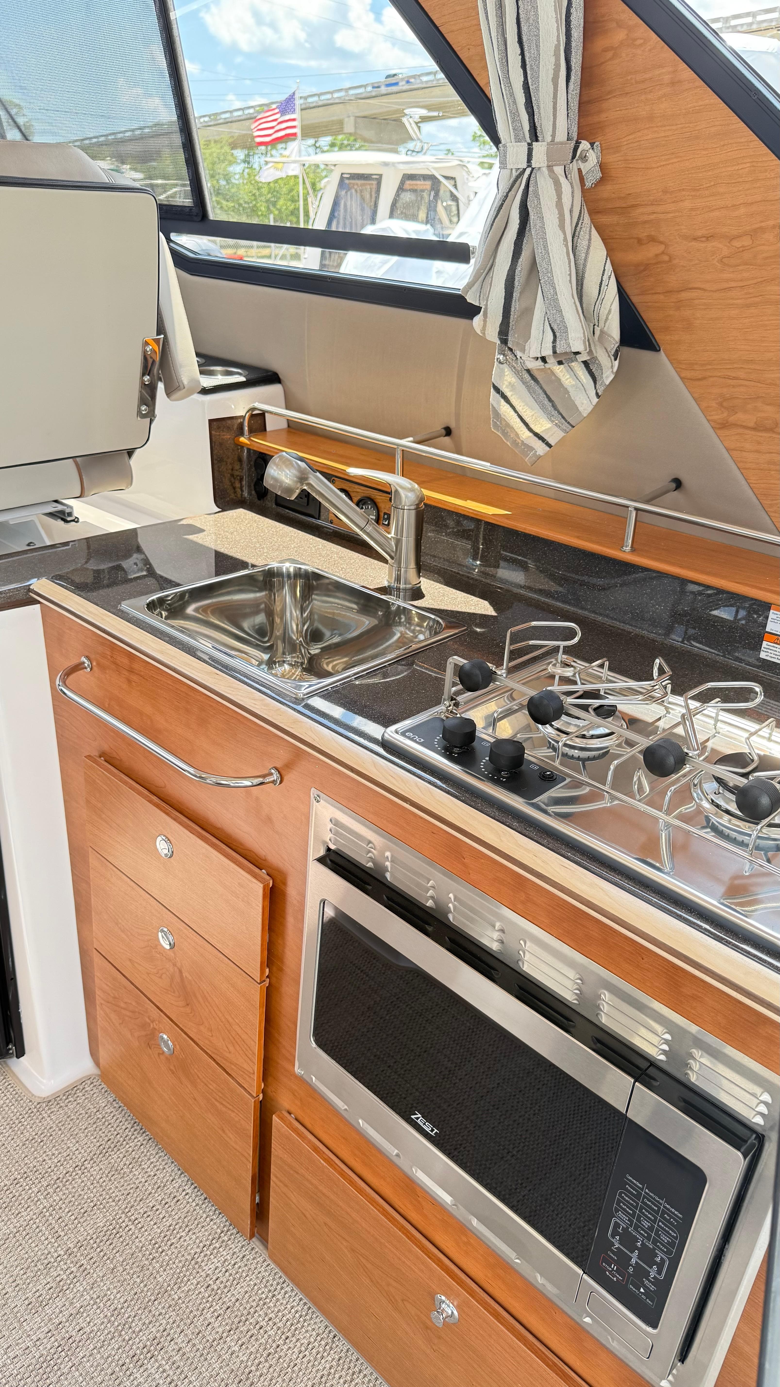 2026 Cutwater C-288 Coupe kitchen with sink, stove, and microwave in a compact, modern design.