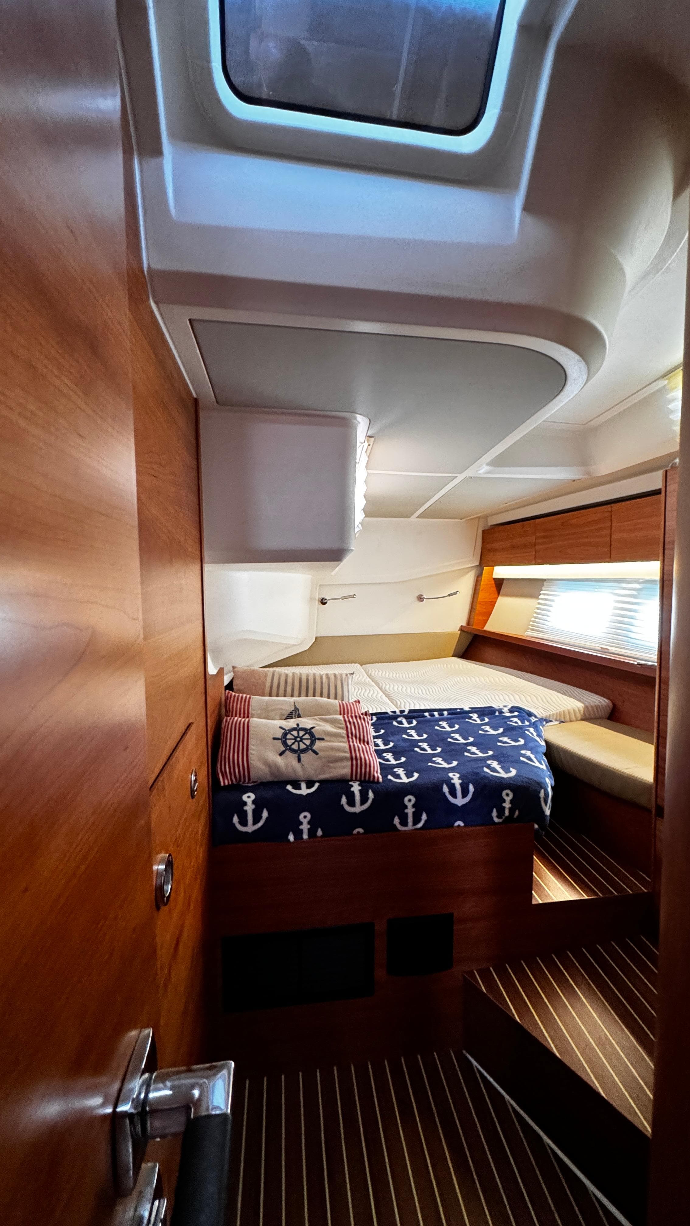 Cozy cabin interior of 2020 Hanse 588 yacht with nautical-themed bedding.