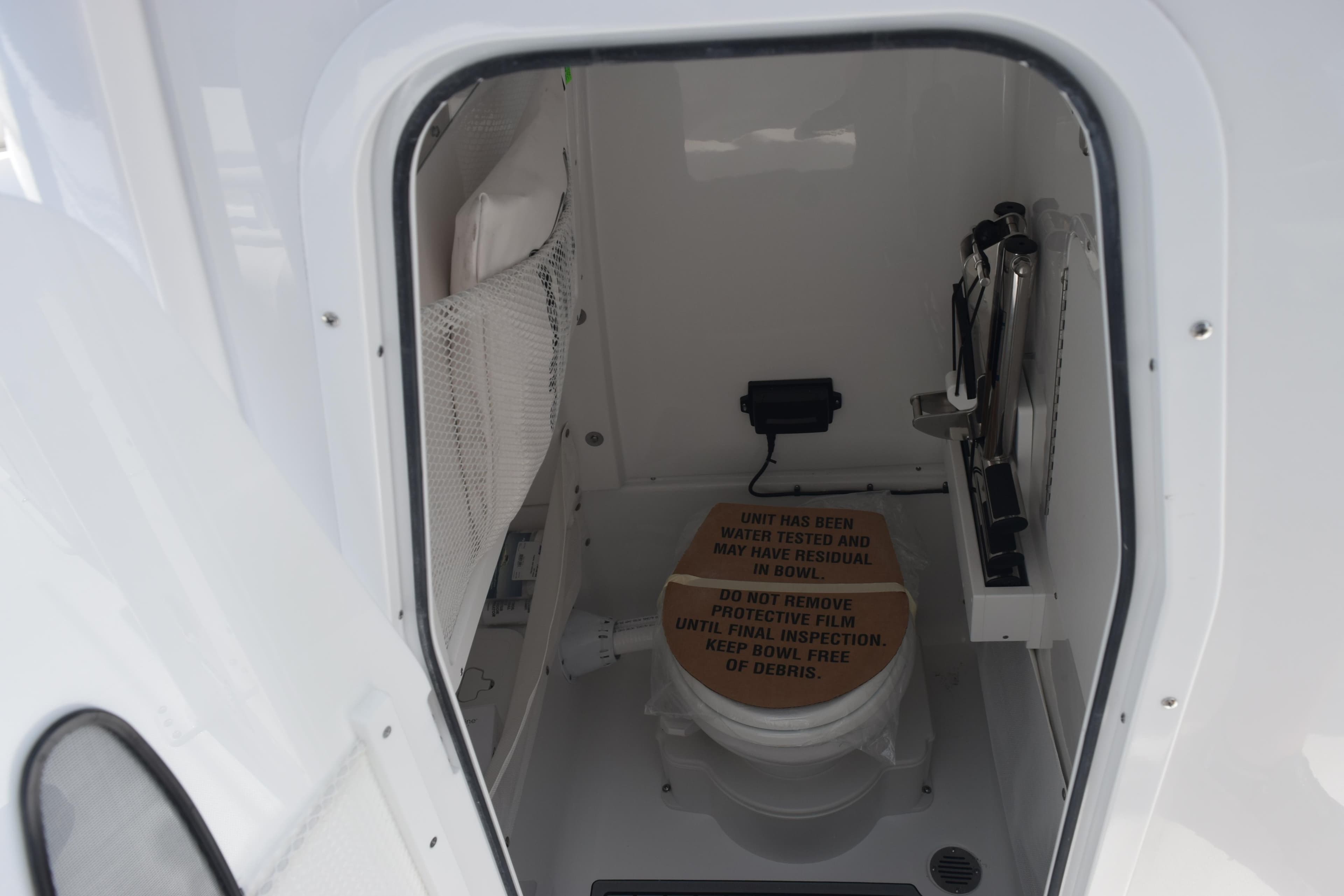 Interior of 2026 Sea Hunt Gamefish 27 boat, featuring a compact marine toilet.