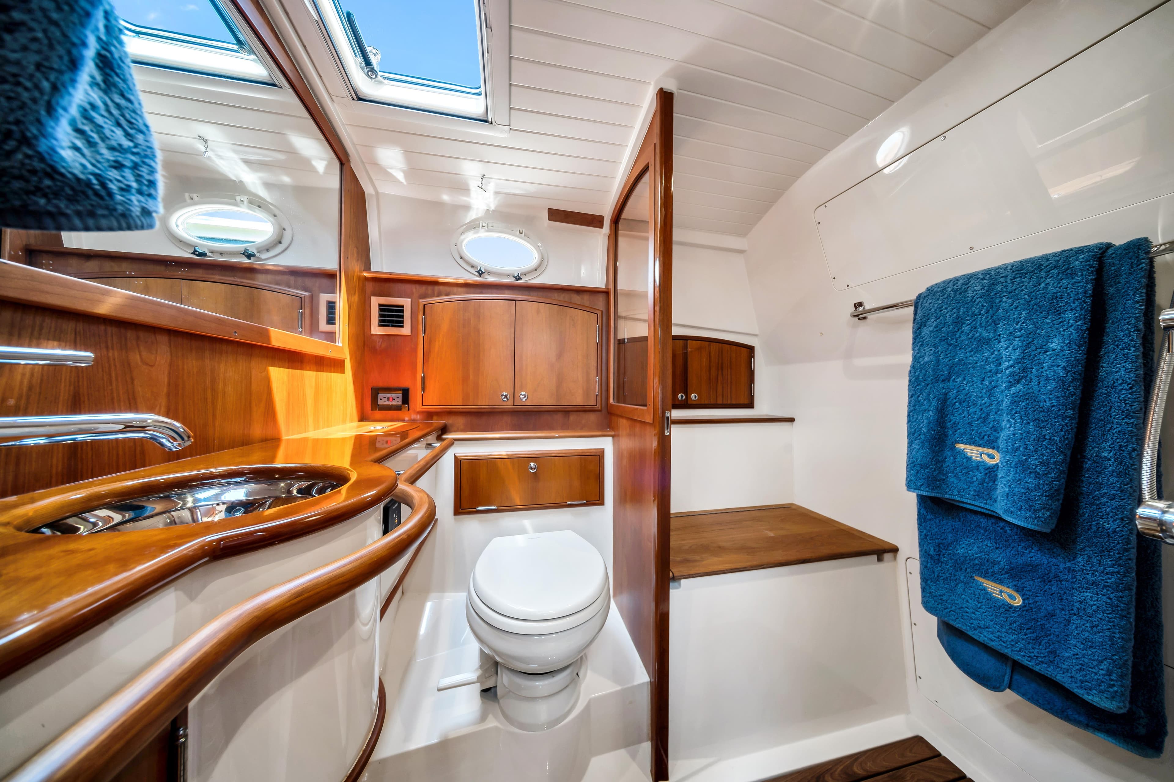 Luxurious 2020 Hinckley Picnic Boat 40 bathroom with wood accents and blue towels.