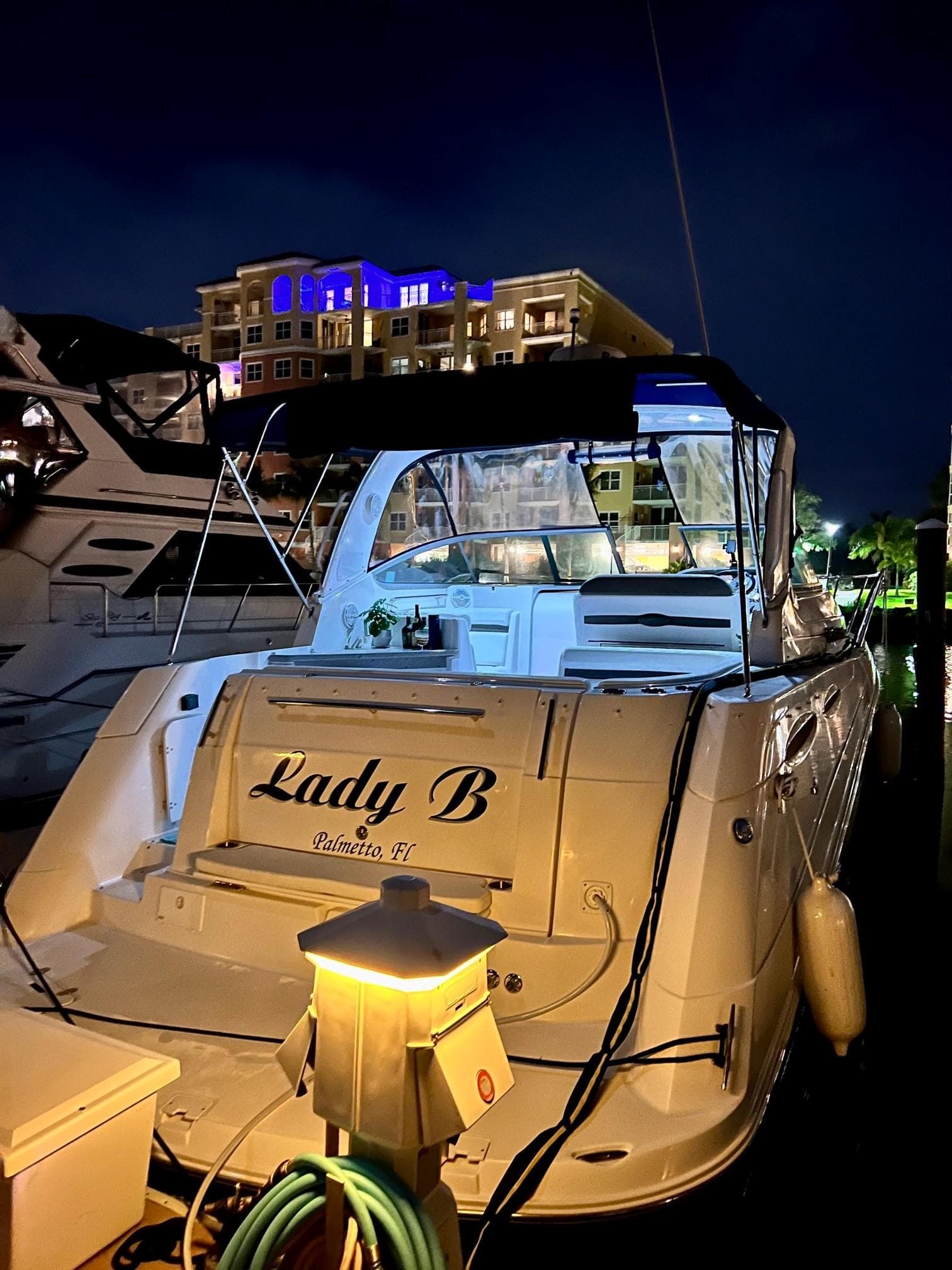 2008 Rinker 350 Express Cruiser docked at night with illuminated buildings in the background.