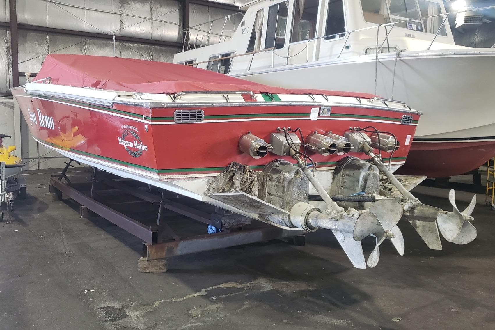 1982 Magnum 40 boat in storage, red cover, dual propellers, indoor setting.