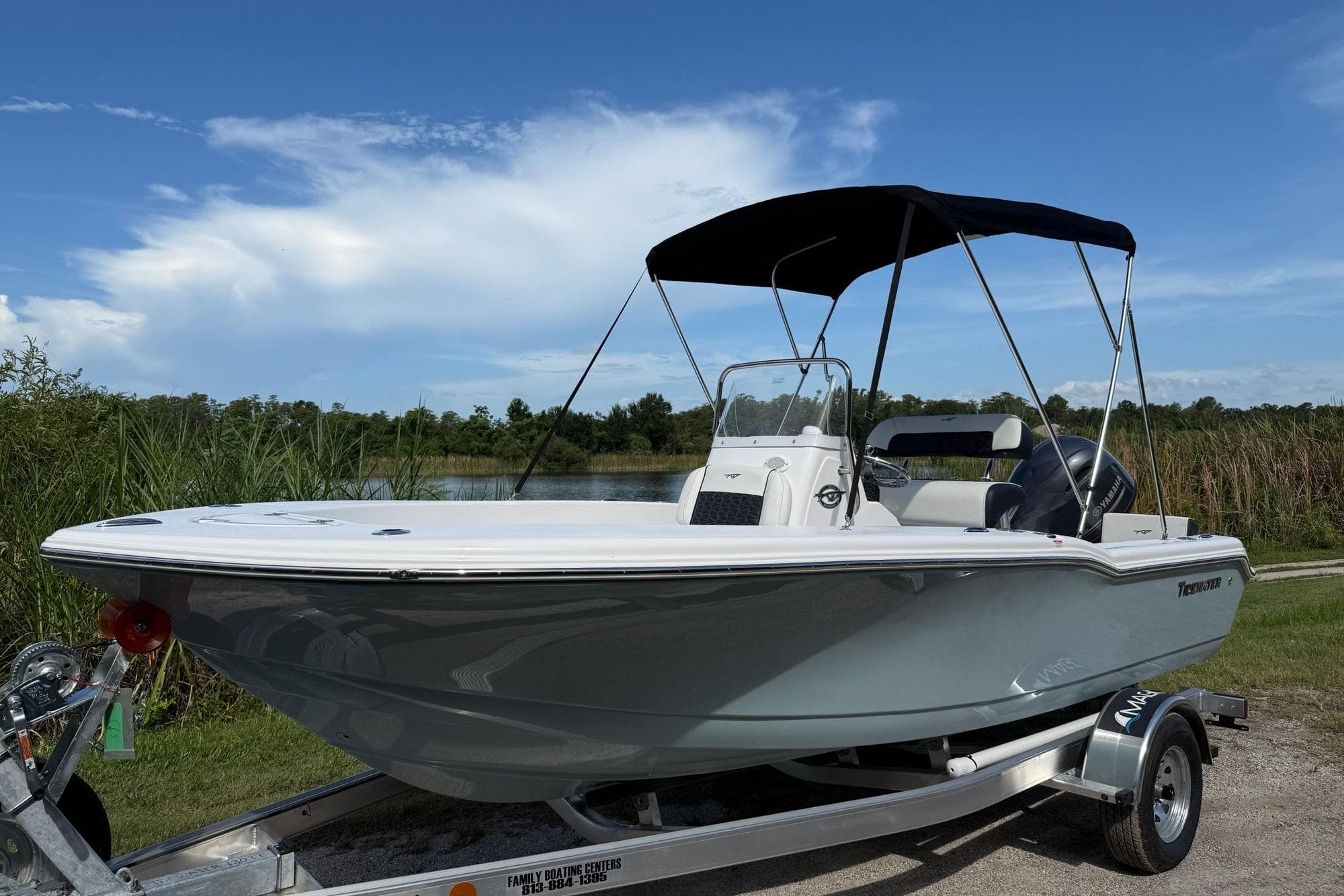 2026 Tidewater 180 CC Adventure boat on trailer, parked near a lake under a blue sky.