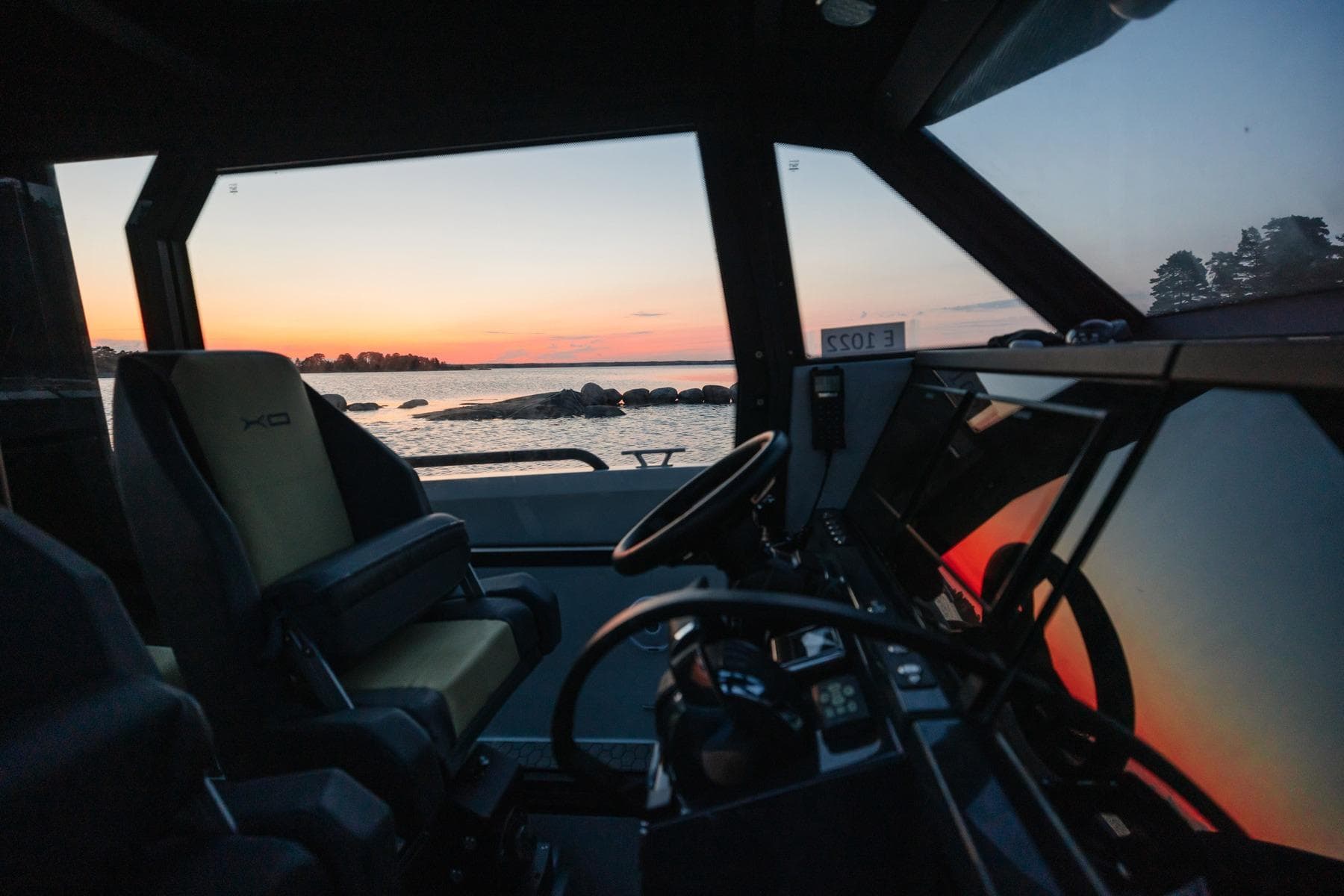 Interior view of 2027 XO DFNDR 9 boat at sunset, showcasing modern design and serene seascape.