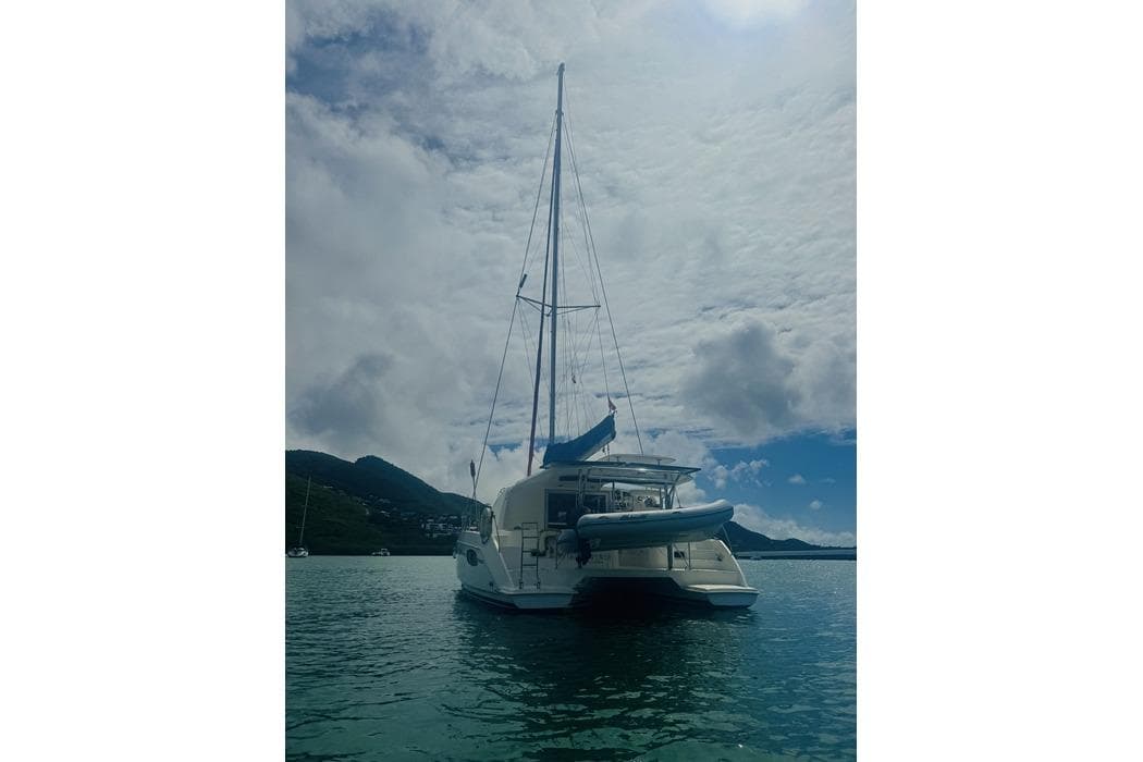 Sailing catamaran Leopard 39, 2011 model, anchored in scenic bay under cloudy sky.