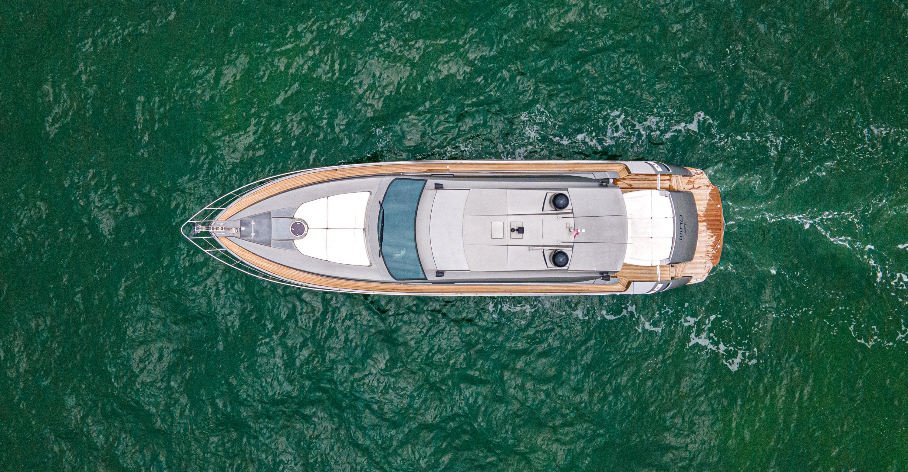 Aerial view of 2009 Pershing 64 yacht cruising on green ocean waters.