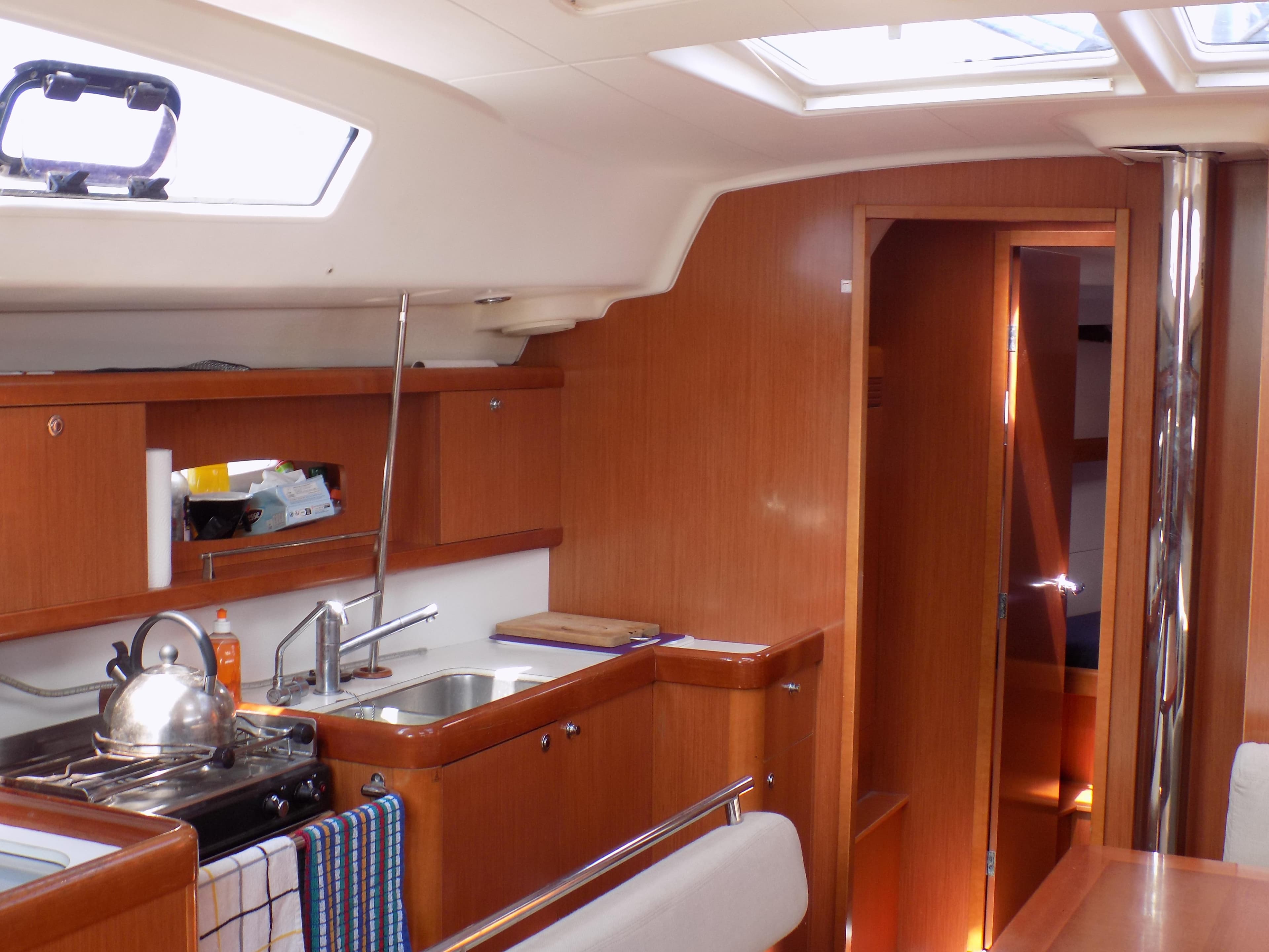 Interior of 2009 Beneteau Oceanis 43 sailboat, featuring kitchen and wooden cabinetry.