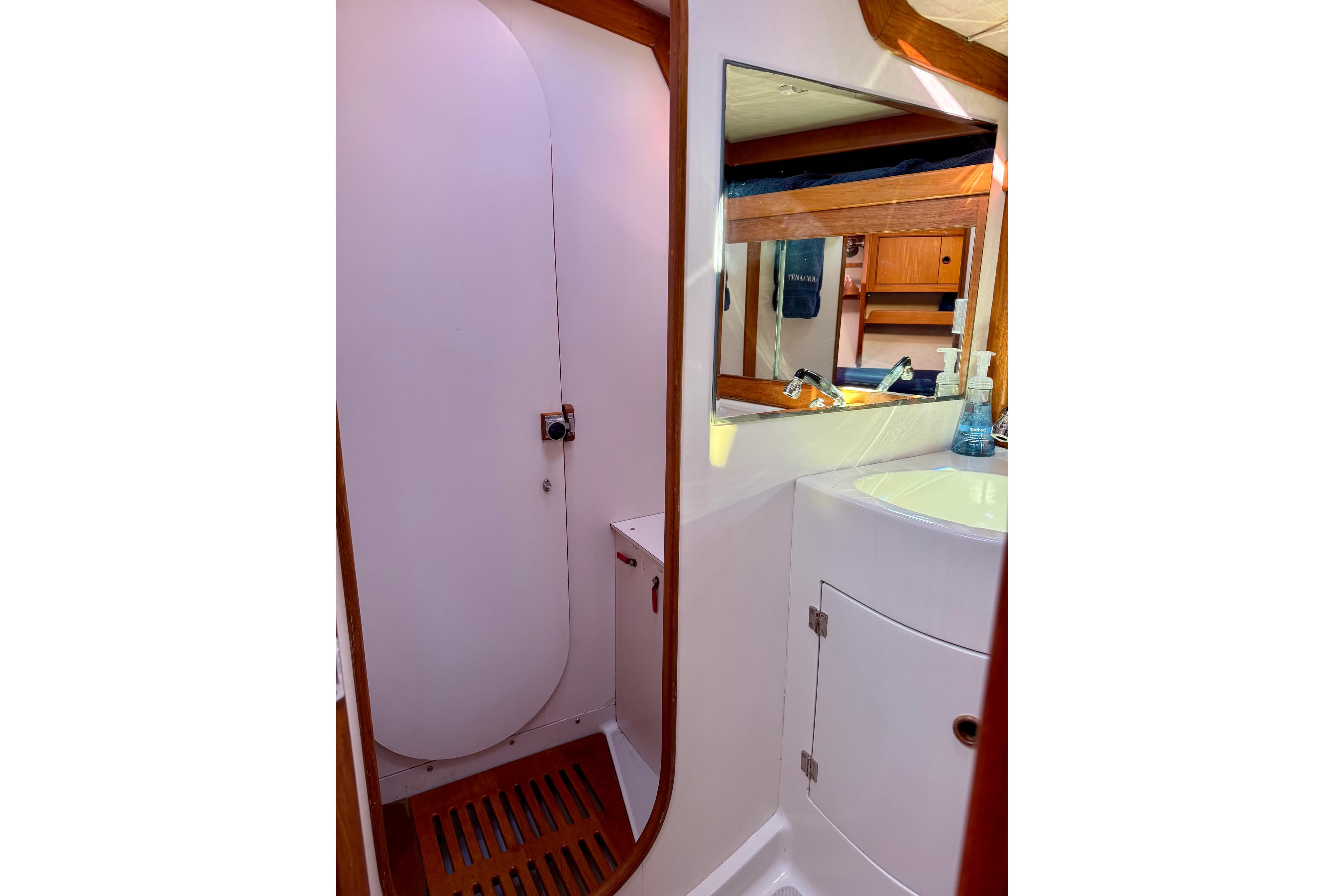 Interior of 1991 J/Boats yacht bathroom with sink, mirror, and wooden accents.