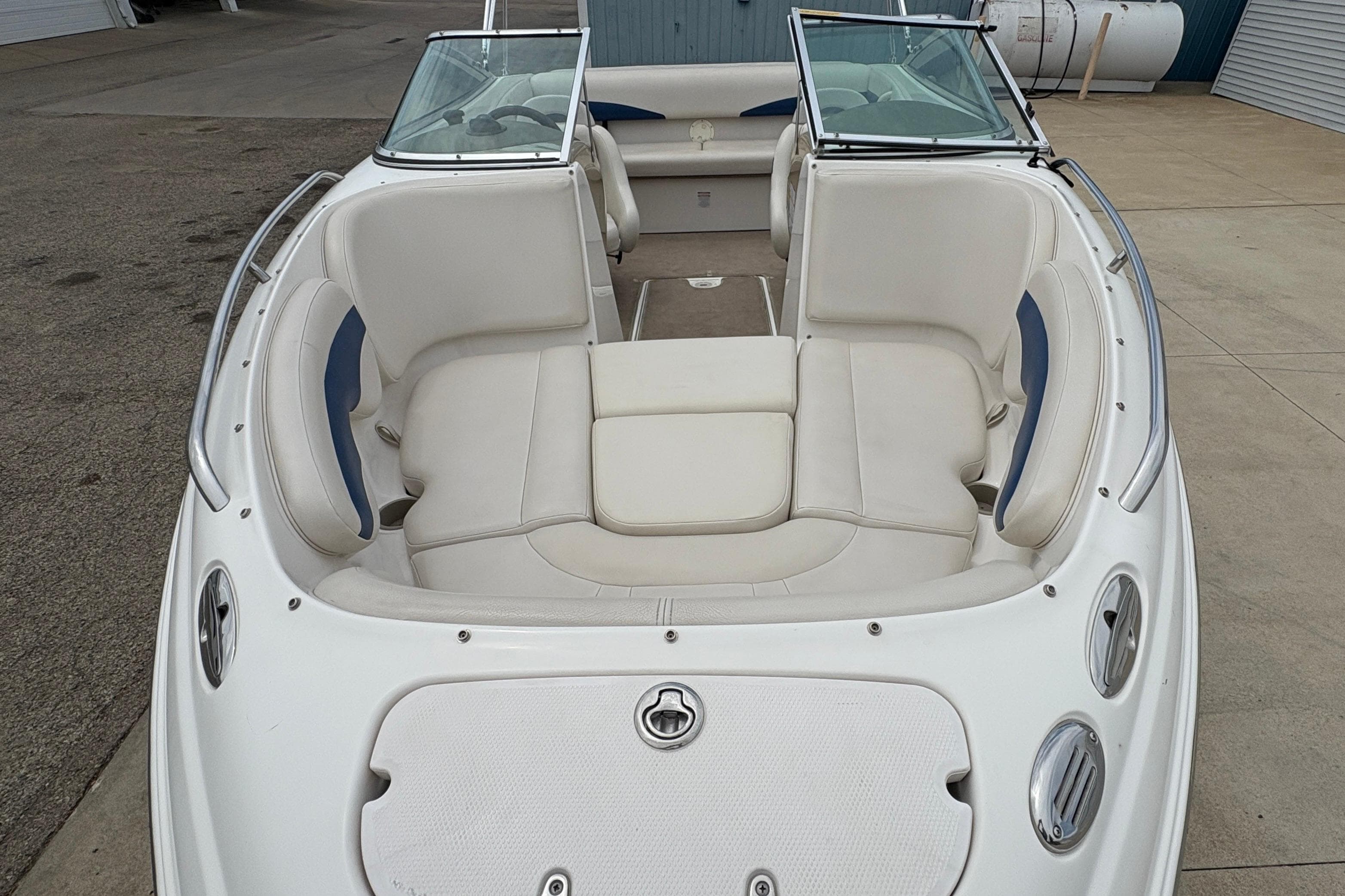 2003 Chaparral 210 SS boat with white seating and windshield, docked on concrete.