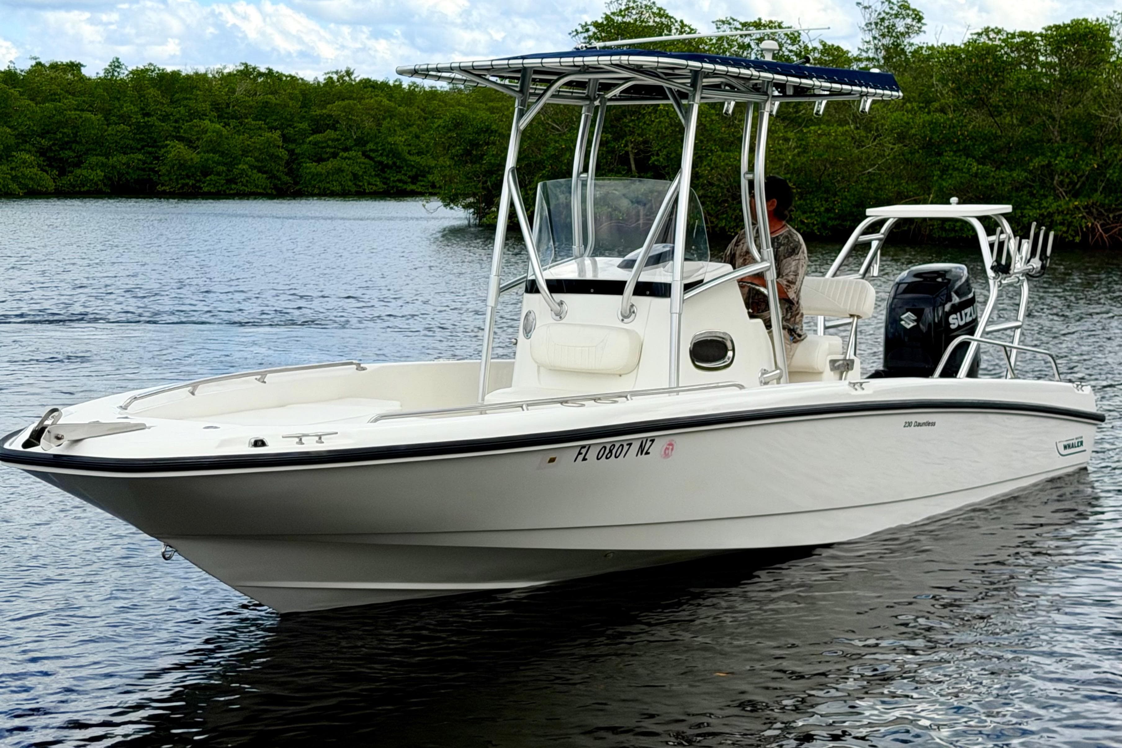 2009 Boston Whaler 230 Dauntless boat on calm water, featuring a sleek design and Suzuki engine.