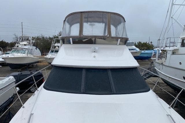 1999 Sea Ray 420 Aft Cabin yacht with enclosed flybridge, docked in a marina.