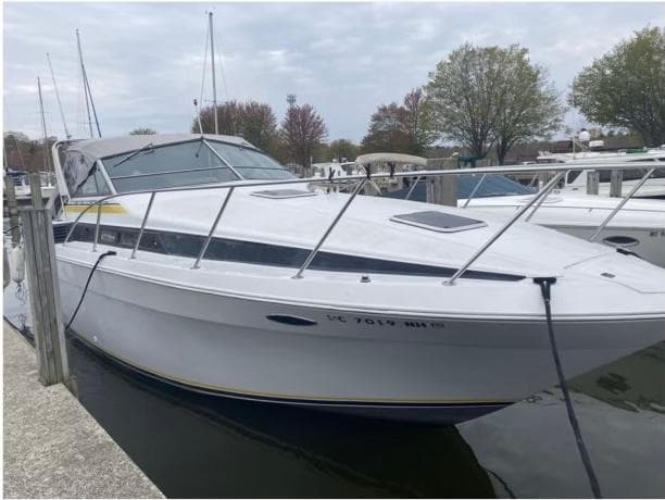 1987 Chris-Craft 320 Amerosport boat docked at marina under cloudy sky.
