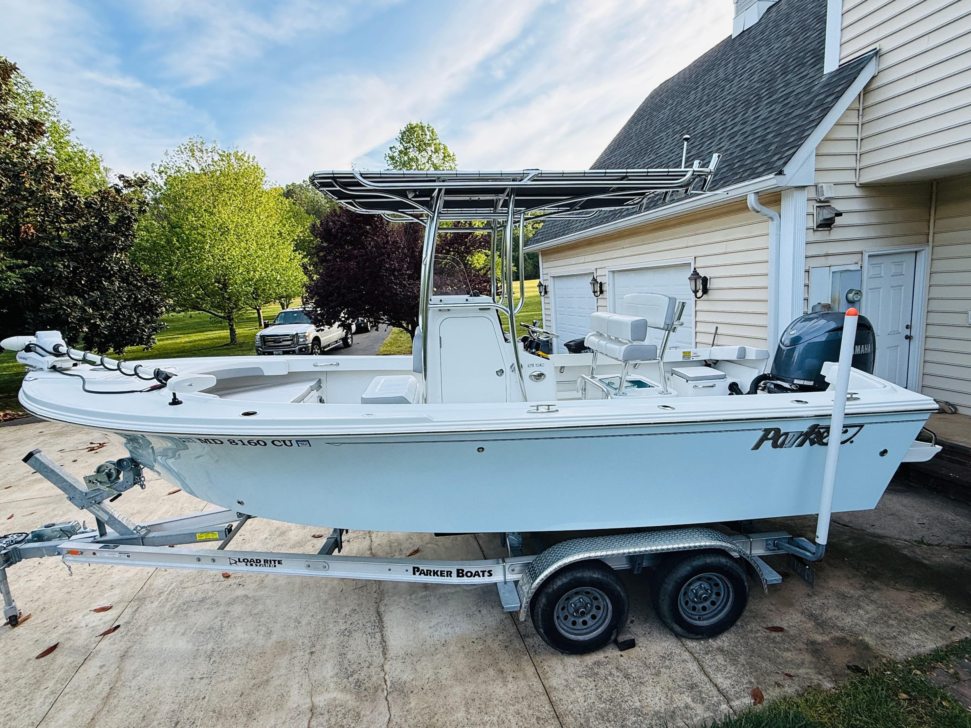 2024 Parker 21 boat on trailer parked beside house.