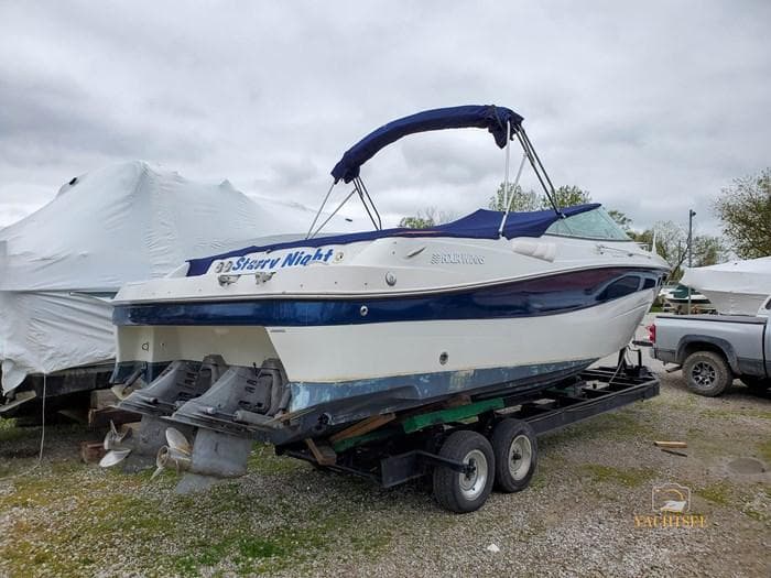 2000 Four Winns 285 Sundowner boat on trailer, blue and white design, parked outdoors.