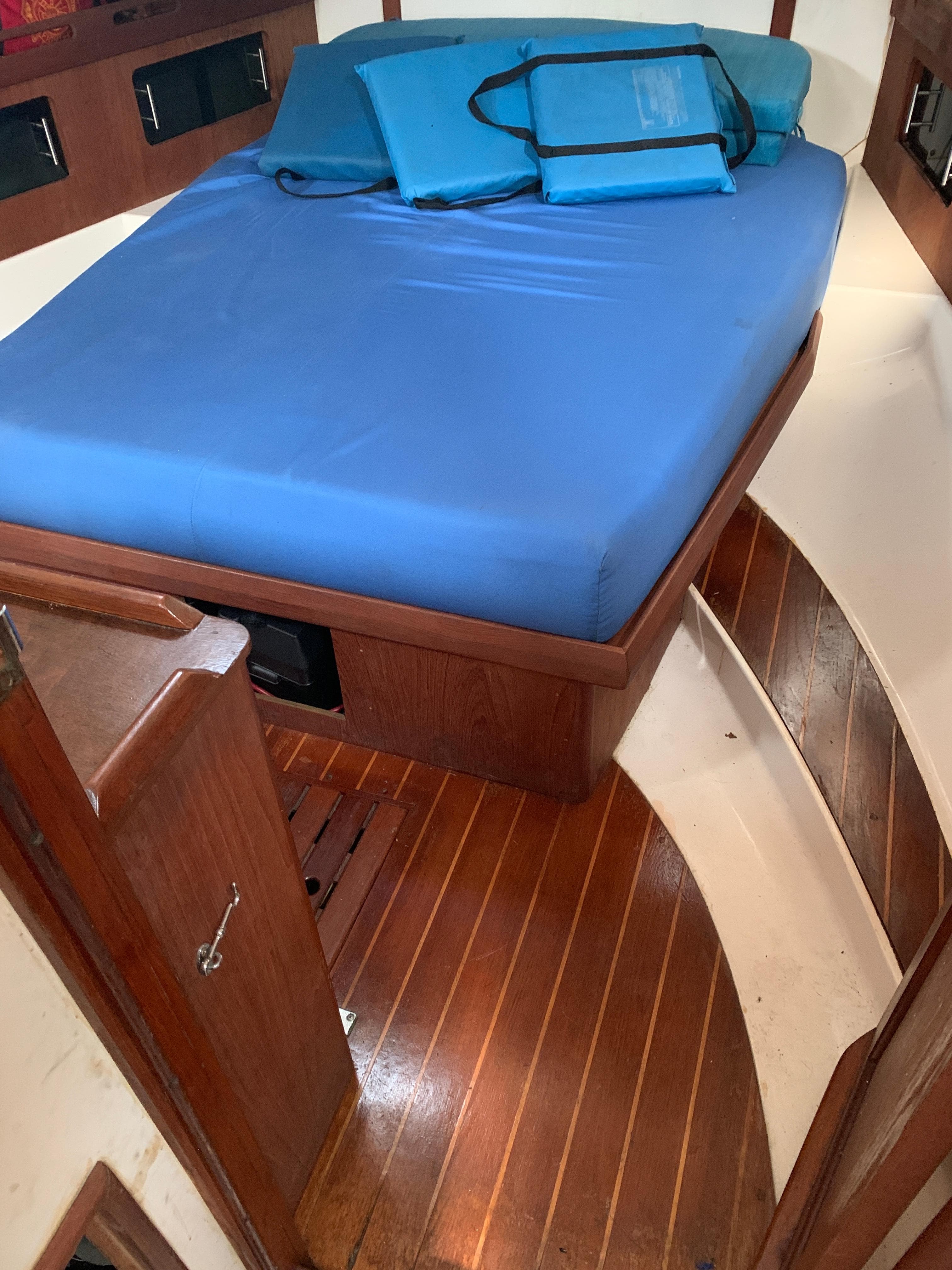 1985 Hunter Legend 40 yacht cabin with blue bedding and wooden flooring.