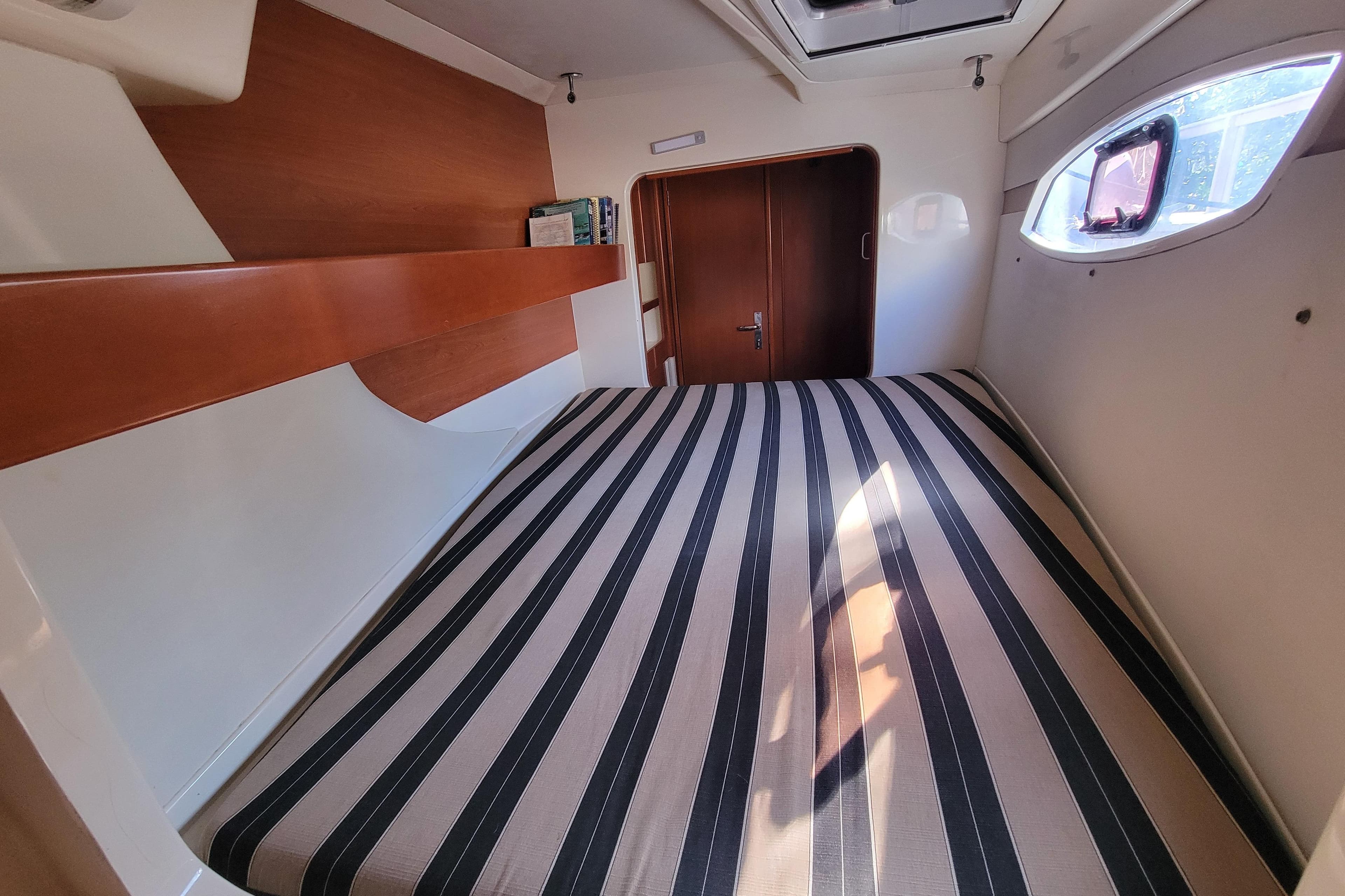 Cozy cabin interior of 2014 Leopard 39 yacht with striped bedding and wooden accents.