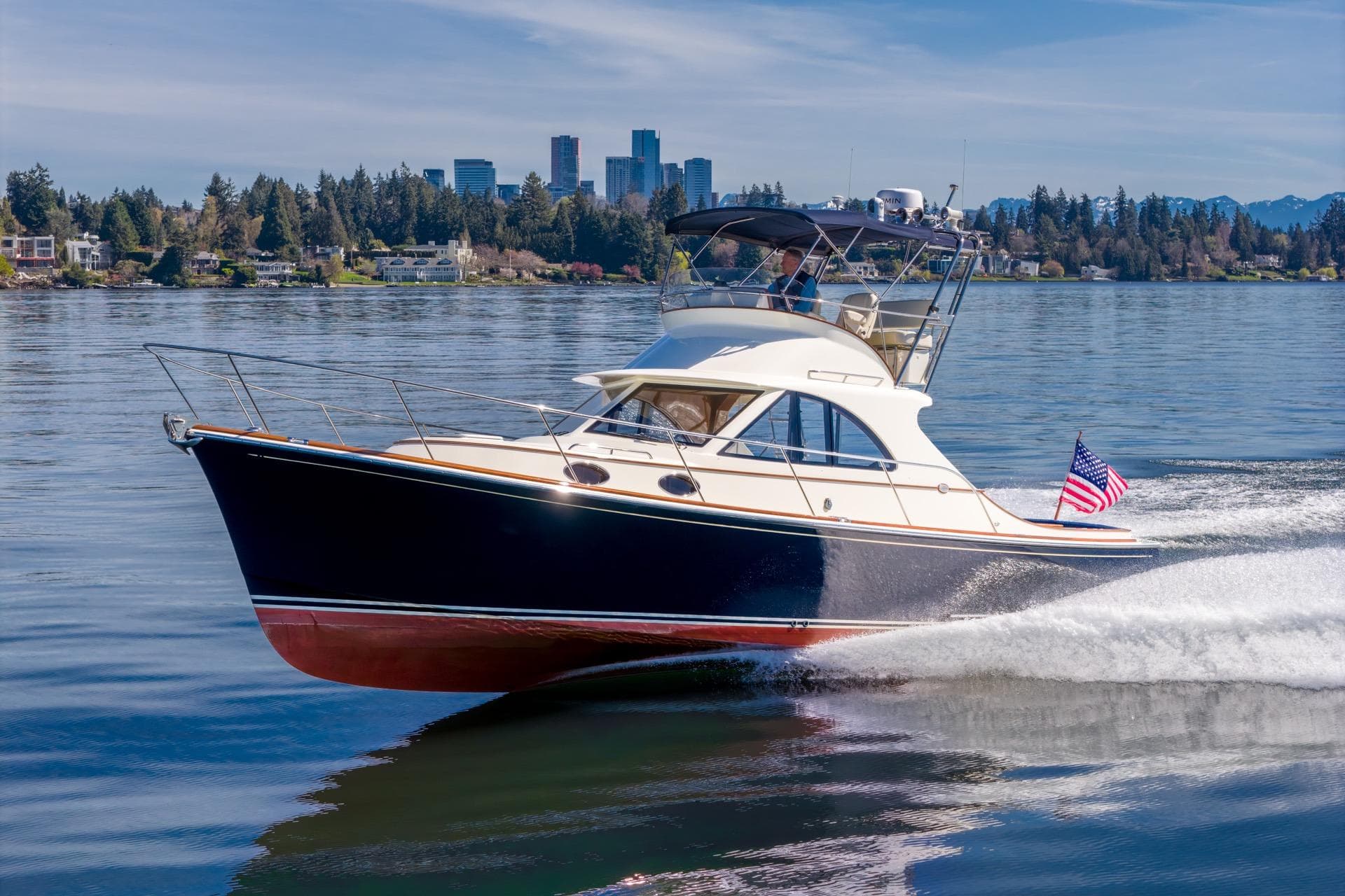 2010 San Juan SJ40FB IPS yacht cruising on a scenic lake with city skyline backdrop.