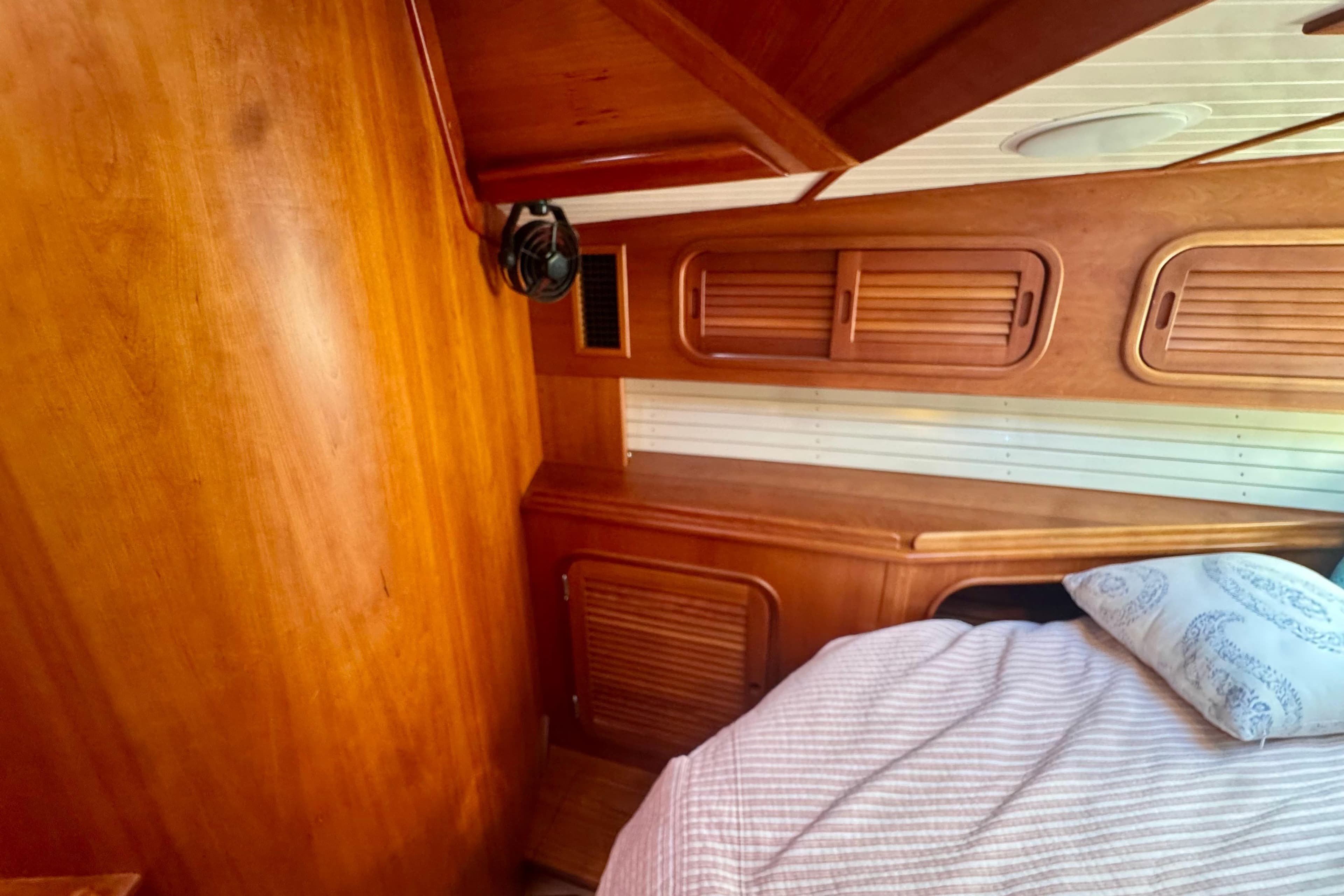 Wood-paneled cabin interior of 1999 Hinckley Sou'wester 52 yacht with bed and fan.