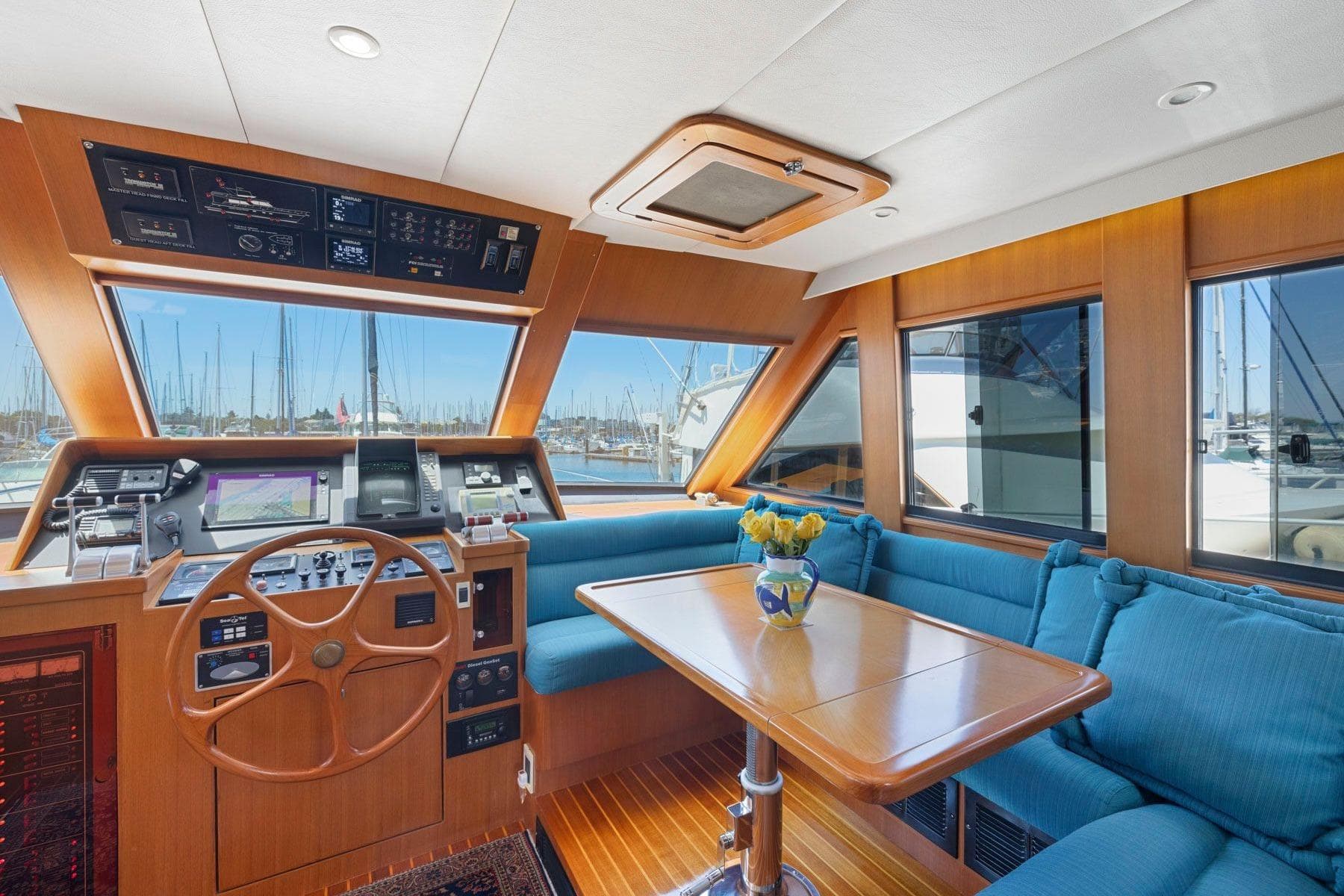 Luxurious 1999 Symbol 55 yacht interior with helm, blue seating, and marina view.