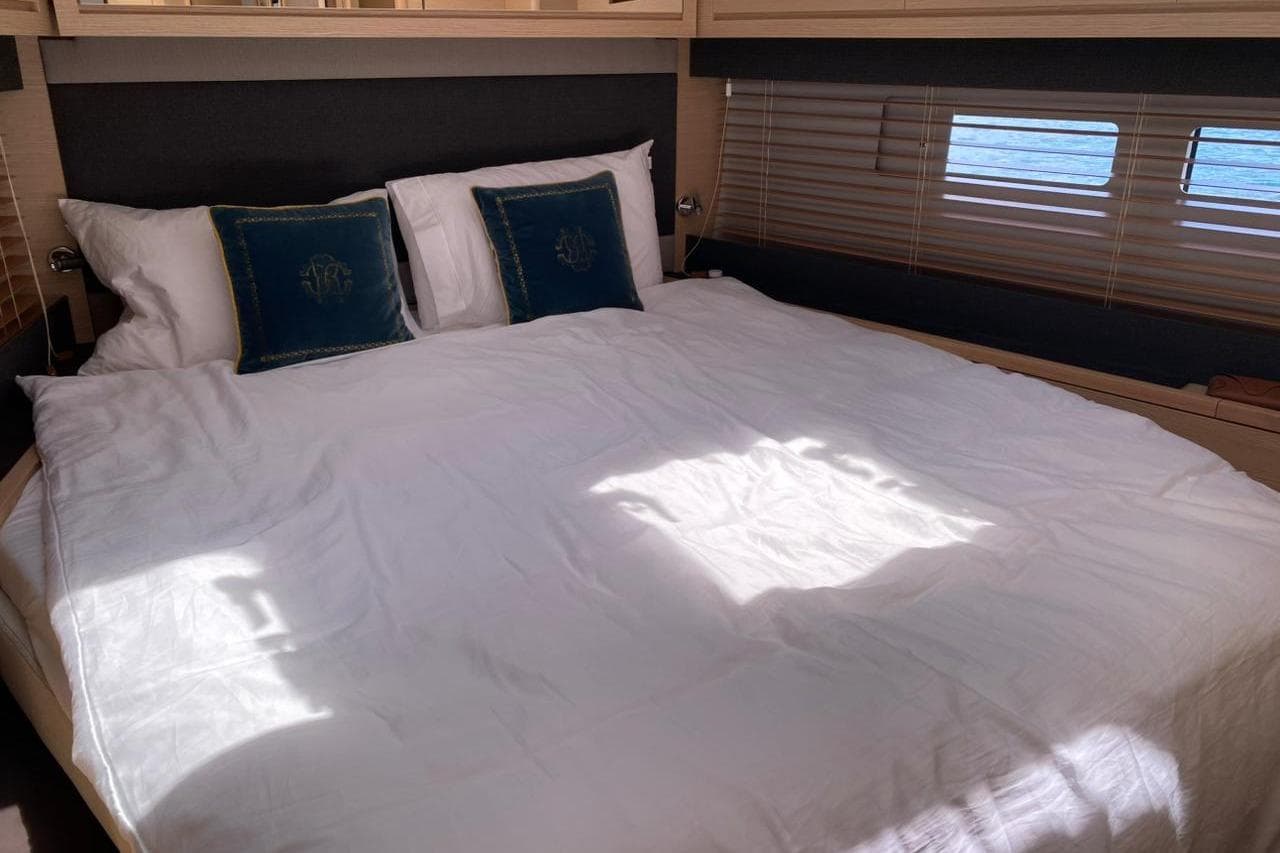 Luxurious bedroom interior of 2021 Dufour 530 yacht with elegant bedding and ocean view.