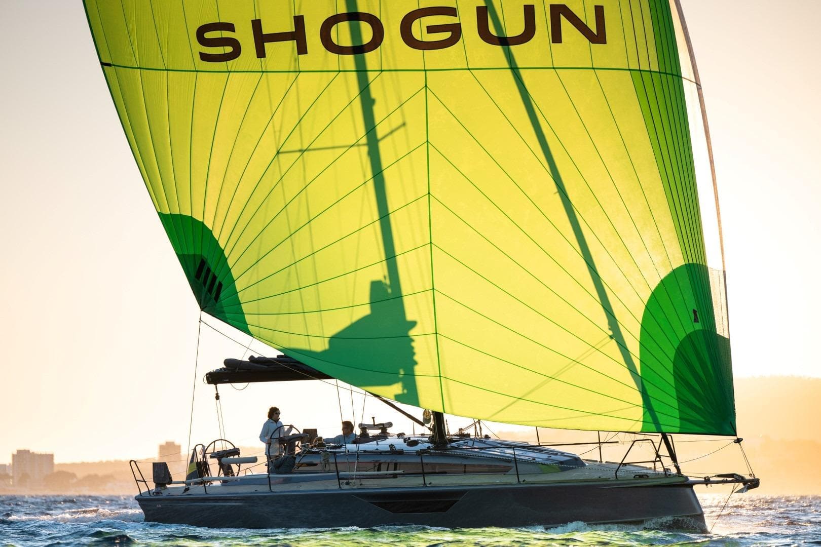 Sailing yacht Shogun 43 with vibrant green sail on open water, 2023 model.