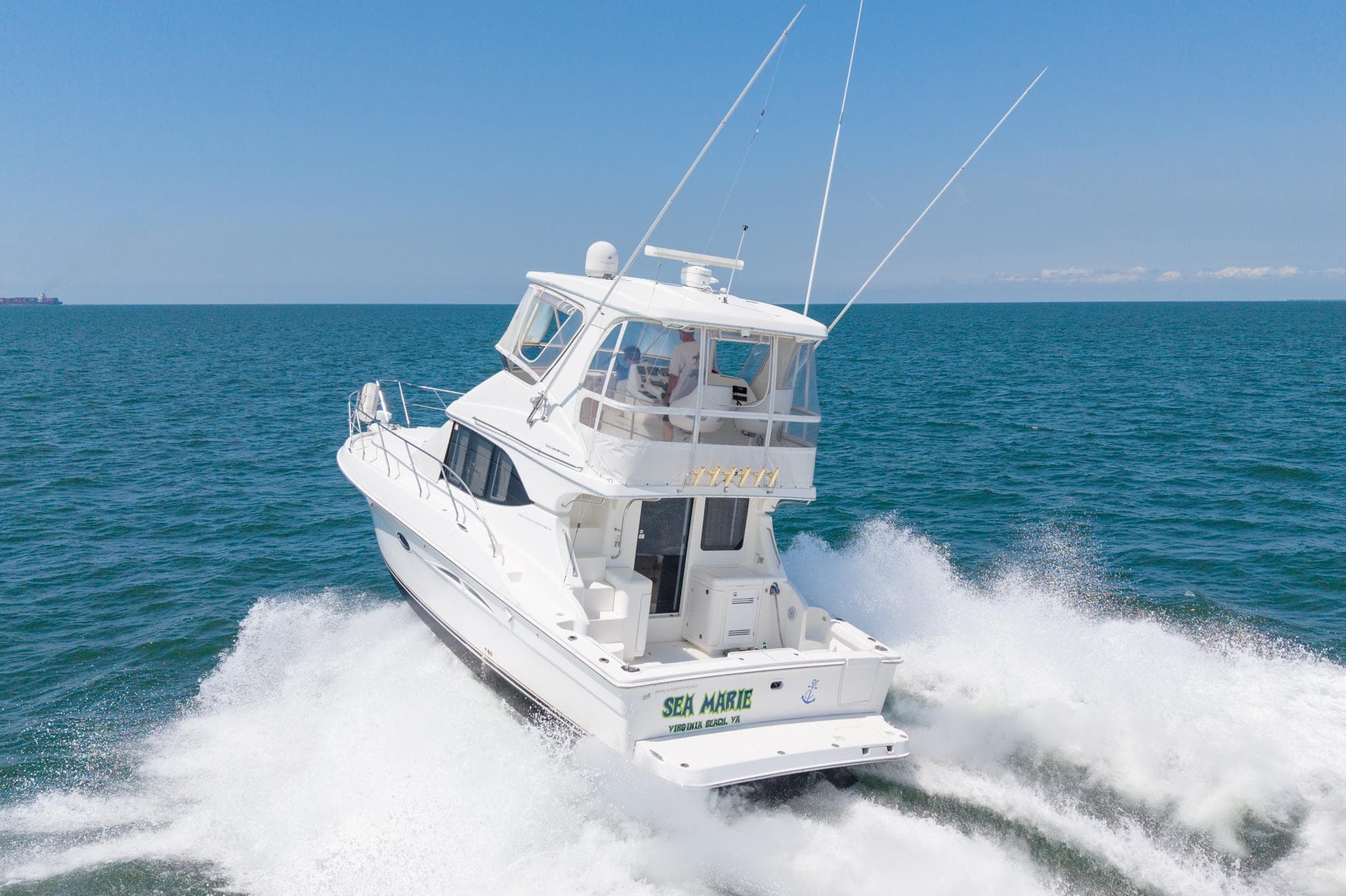2007 Silverton 38 Convertible yacht cruising on open sea under clear blue sky.