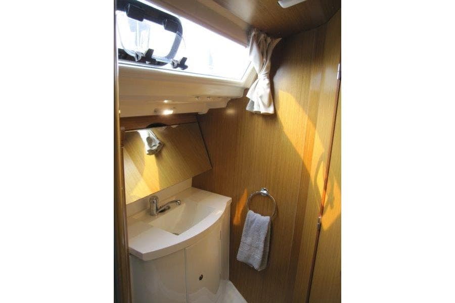 Compact bathroom in 2008 Jeanneau Sun Odyssey 39i yacht with wooden finish and natural light.