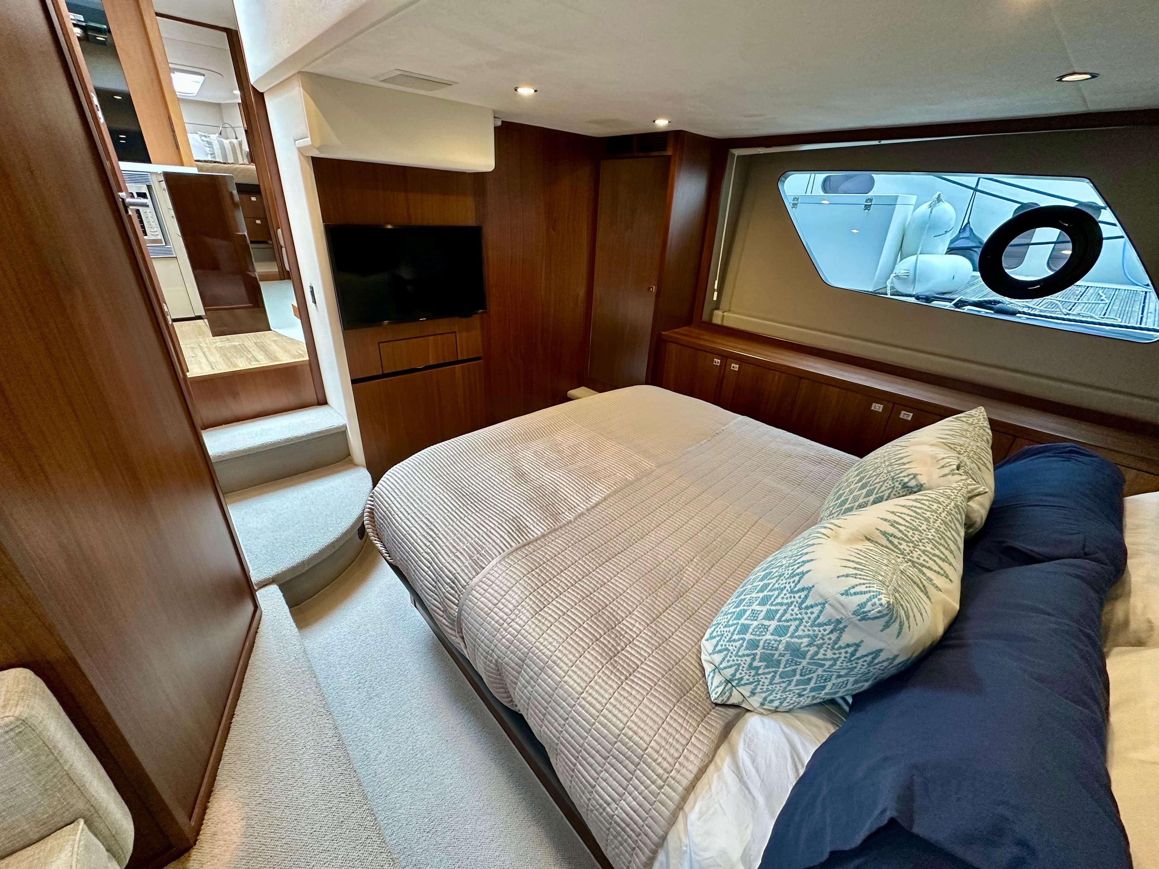 Luxurious bedroom interior of 2014 Princess V52 yacht with elegant wood finishes and large window.