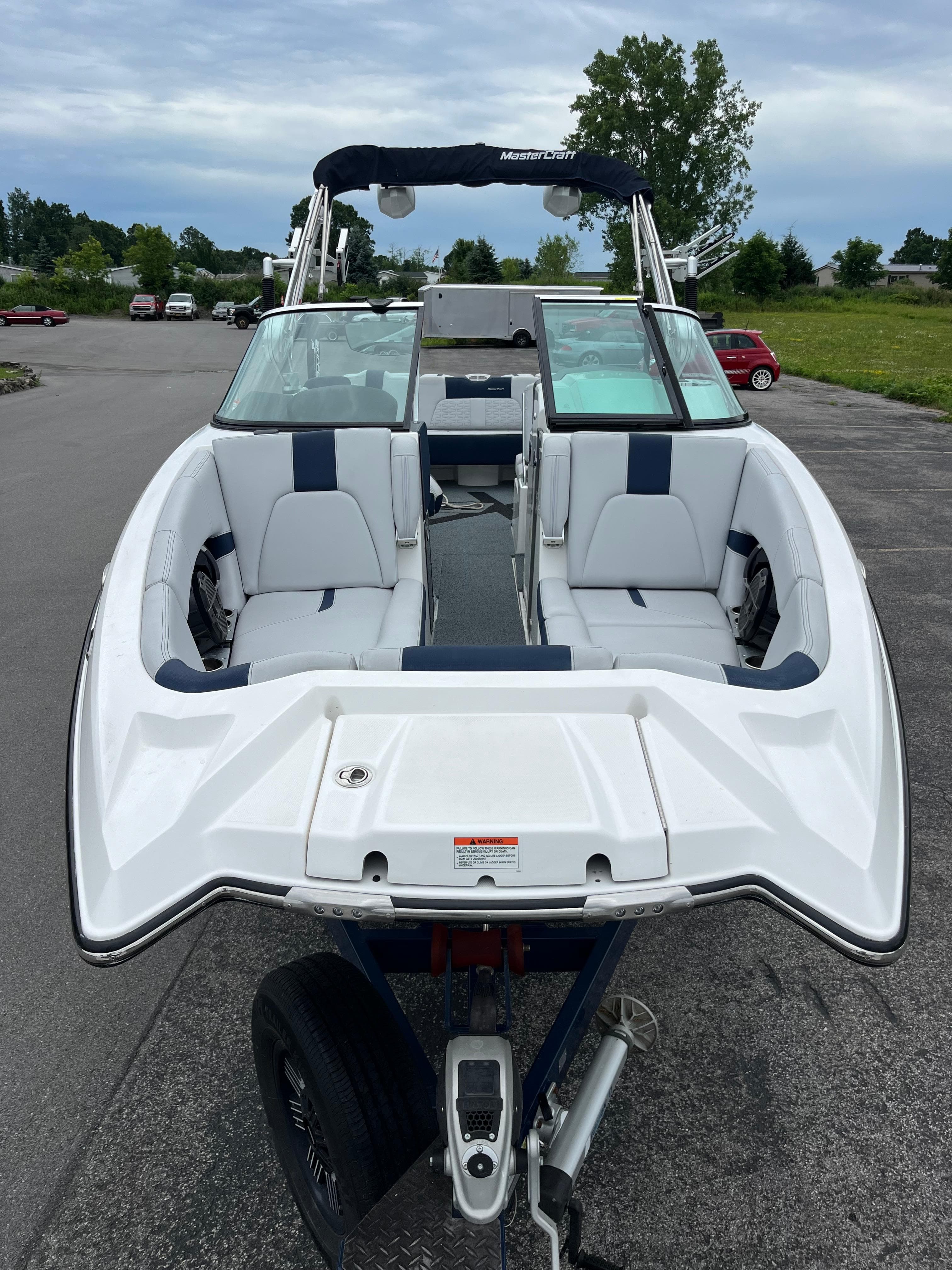 2019 MasterCraft X26 boat with white and blue seating, parked on a trailer.