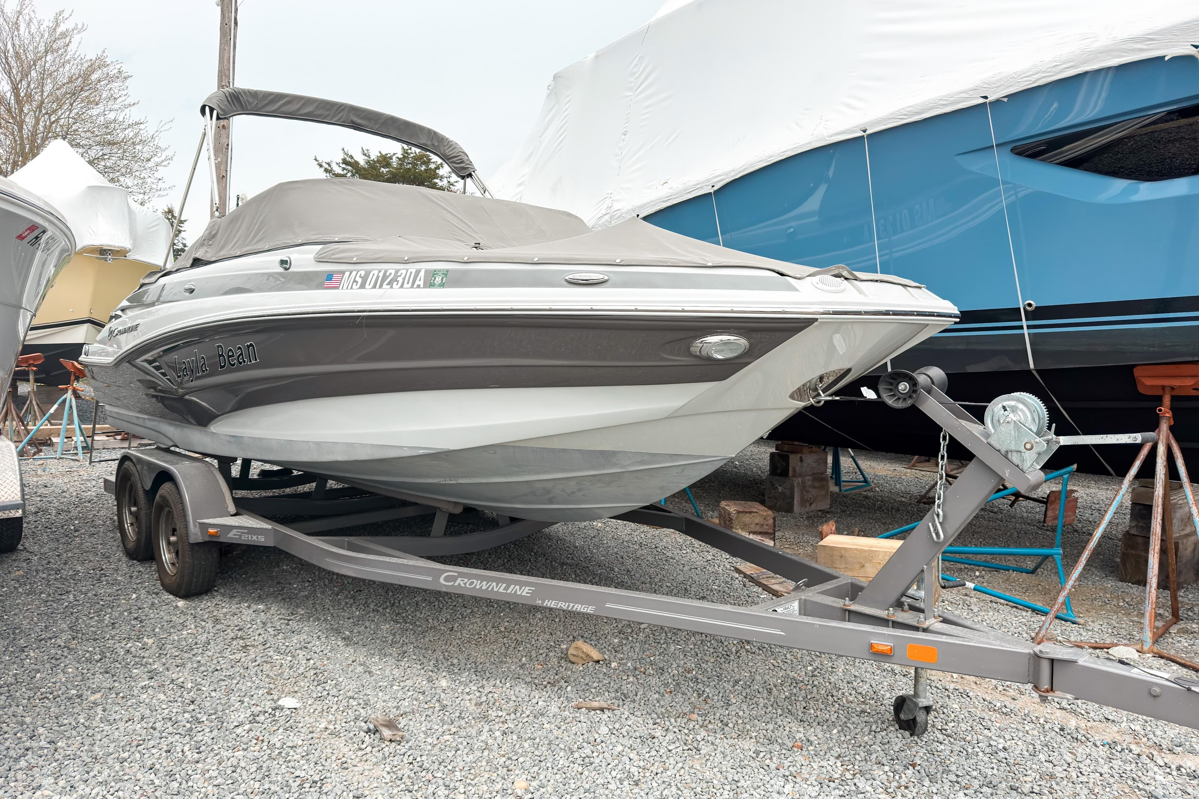 2018 Crownline Eclipse E215 XS boat on trailer, covered and parked on gravel.